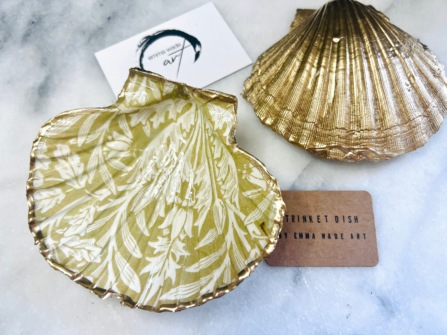 Handmade scallop shell trinket dishes featuring a William Morris gold and ivory acorn heritage pattern with shimmering liquid gold leaf edging. Natural Dorset scallop shells sealed in glossy crystal clear resin and styled as luxury jewellery holders, vanity trays and coastal home décor accessories. Elegant Arts and Crafts inspired shell dishes photographed on a marble background with pearls and decorative styling.
