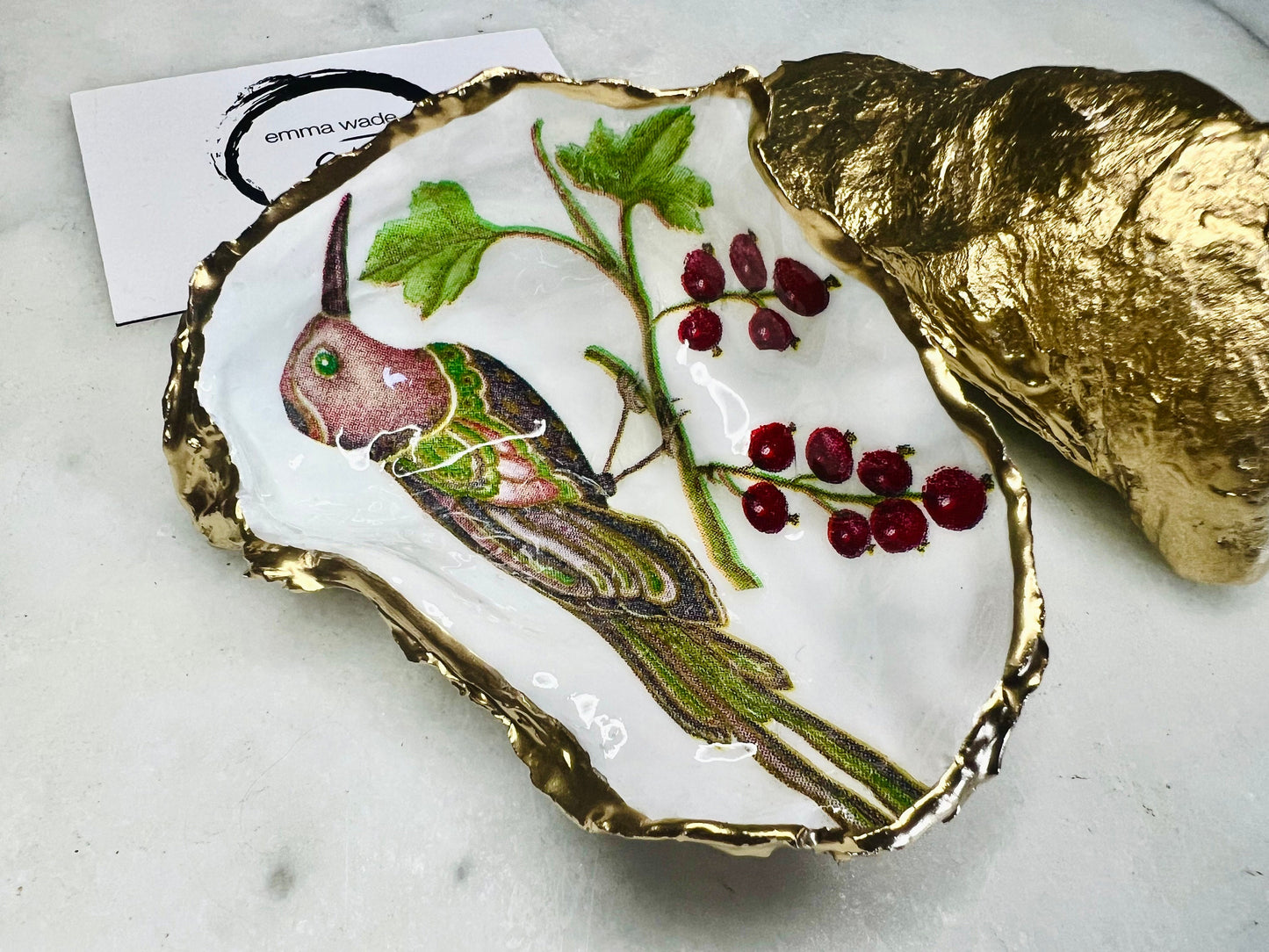 Handmade Dorset oyster shell trinket dish featuring Birds of Paradise illustration with green and brown bird designs, hand gilded with liquid gold leaf on the rim and reverse, sealed with glossy crystal clear resin, coastal jewellery holder, botanical bird decor, nature inspired oyster shell gift UK