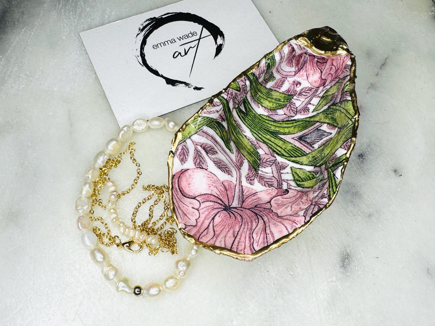 Single handcrafted Dorset oyster shell trinket dish featuring the William Morris Pink Pimpernel design in pink and green tones, edged with liquid gold leaf and sealed in glossy resin. Sold individually, this natural oyster shell jewellery holder is ideal for rings or earrings and makes a unique coastal gift or wedding favour.