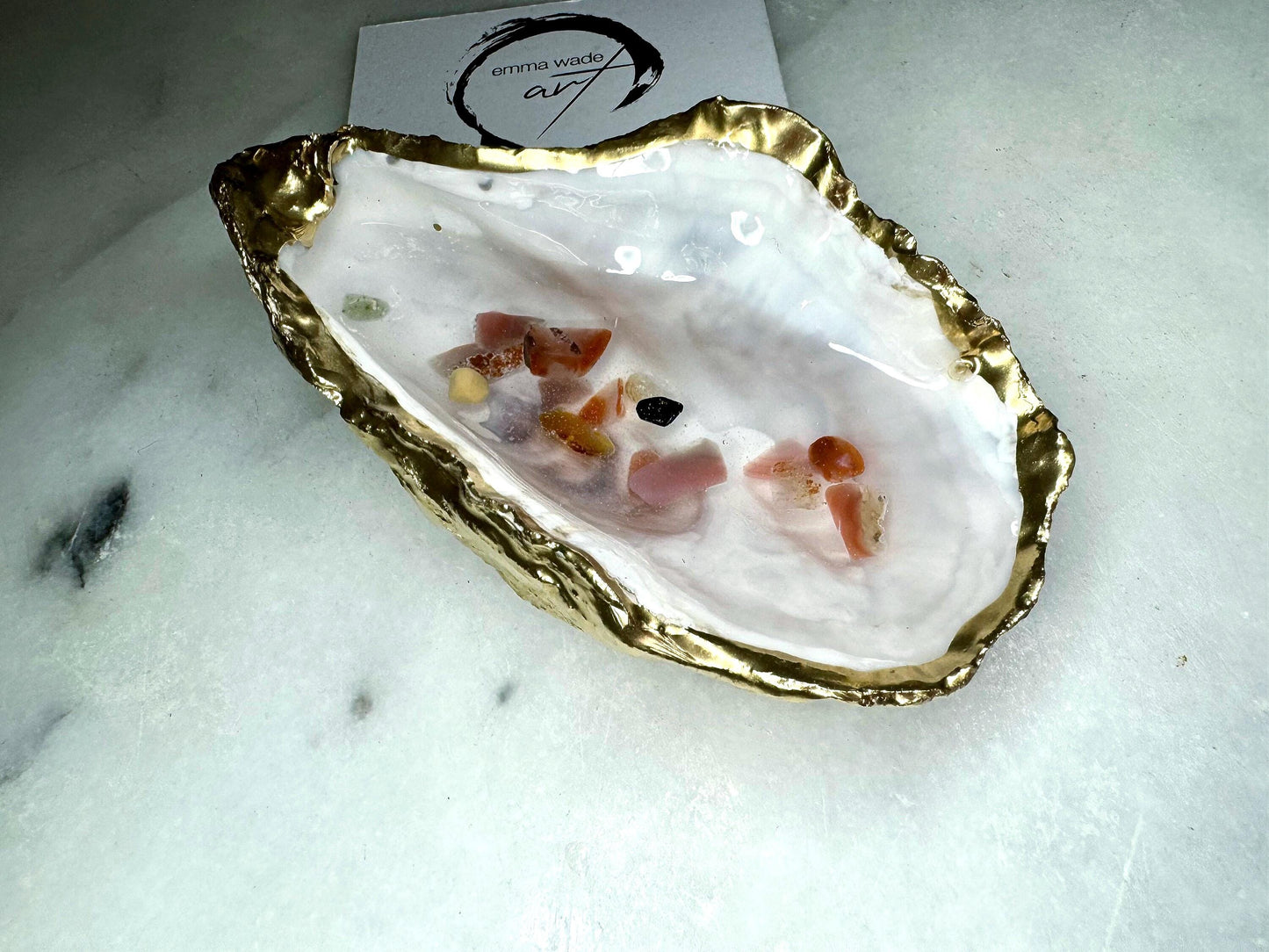 Handmade oyster shell jewellery dish with real Dorset sea glass foraged from the coast and suspended in clear glossy resin to look like a rock pool. Finished with gold leaf trim and a natural pearl interior, this unique shell dish can be used as a ring holder, jewellery tray, or trinket catcher for earrings, cufflinks, or keepsakes. A one-of-a-kind coastal-inspired gift for weddings, anniversaries, birthdays, bridesmaids, Christmas, or Mother’s Day.