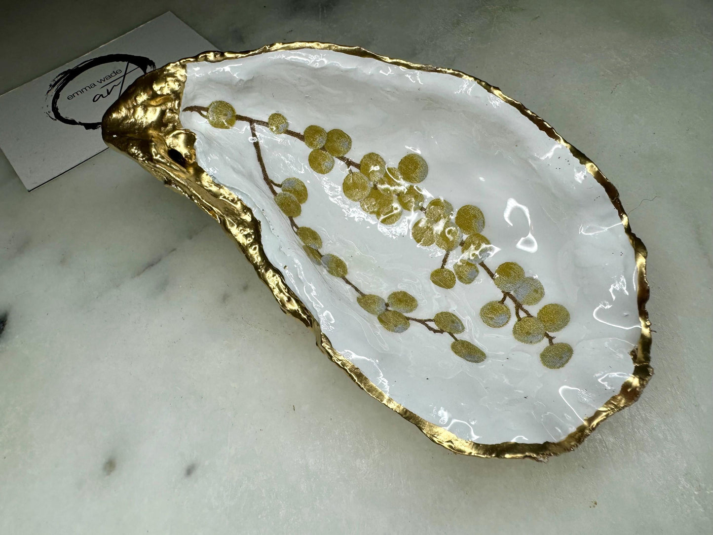 Handmade Dorset oyster shell dish with a gold and white berries design, gilded with liquid gold leaf on the rim and back, and sealed in crystal-clear resin for a glossy shine. Each oyster shell jewellery dish is unique, perfect as a ring holder, trinket tray, or organiser for earrings, cufflinks, and small keepsakes. A meaningful handmade oyster ring dish for weddings, anniversaries, birthdays, bridesmaids, or festive celebrations. Ideal as UK coastal-inspired home décor.