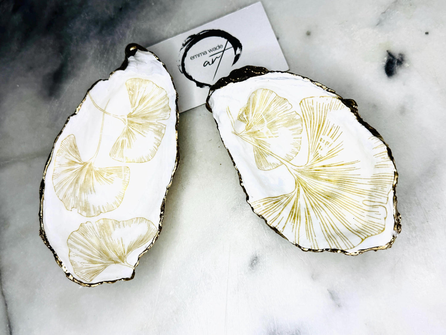 Pair of handmade Dorset oyster shell salt and pepper pinch pots featuring elegant Japanese Ginkgo floral artwork in soft gold and pearl tones with hand-applied gold leaf edging. Coastal luxury cruet set sealed in glossy Crystal resin with optional gold crystal spoons.