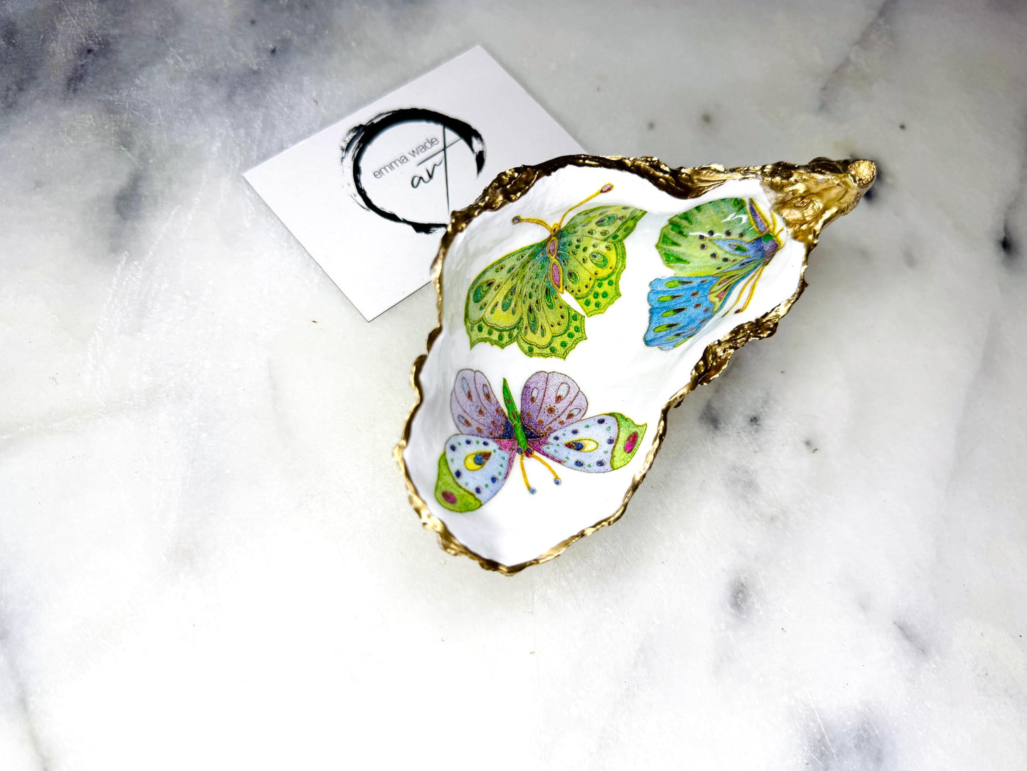 Handmade butterfly oyster shell trinket dish with colourful blue green and pink butterfly designs, edged and backed in gold leaf, Dorset coastal shell jewellery holder with glossy resin finish, luxury ring dish, coastal home decor gift, unique handmade shell dish for jewellery storage, beach house accessory, UK artisan oyster shell dish