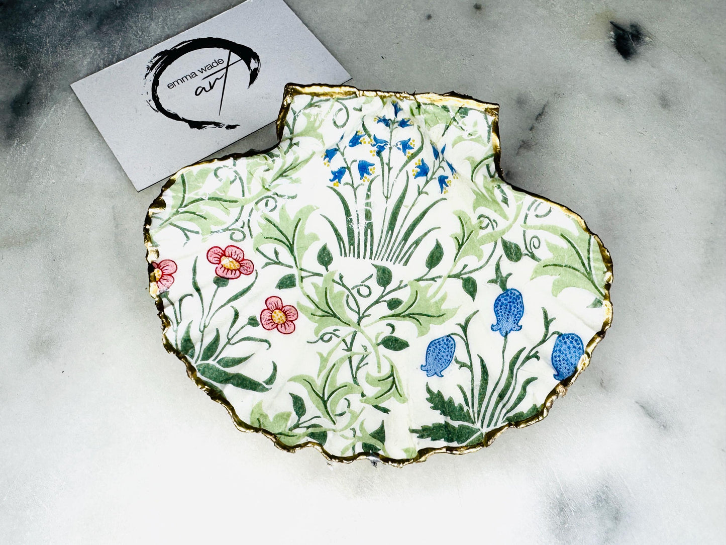 Handcrafted Dorset scallop shell dish featuring William Morris Compton botanical artwork with flowing green foliage and floral details. Natural scallop shell hand-finished with real liquid gold leaf edging and reverse, sealed beneath crystal-clear glossy resin. Luxury jewellery dish, ring holder and trinket tray for coastal, cottagecore and Arts & Crafts inspired interiors. Available in small and large scallop shell sizes.