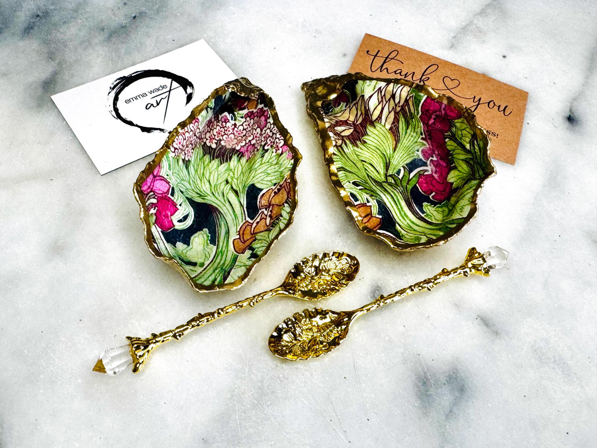 Handcrafted pair of oyster shell salt and pepper pinch pots featuring the Forest Trees botanical design in rich green, pink, cream and gold tones. Natural Dorset oyster shells hand-finished with liquid gold leaf edging and sealed beneath a crystal-clear resin for a glossy finish. Includes optional gold crystal spoons. Elegant table decor for dining, entertaining, weddings, anniversaries and housewarming gifts. Handmade in Surrey, England by Emma Wade ART.