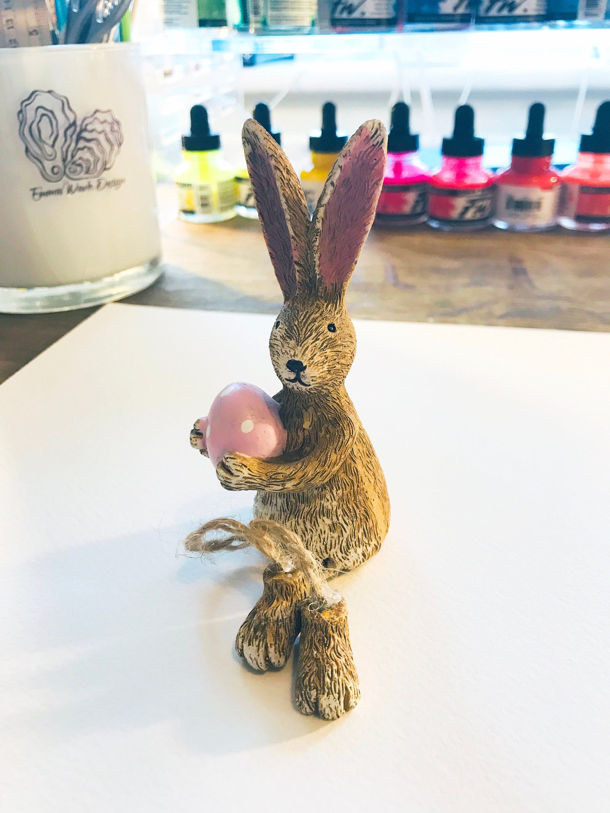 Hand-finished shelf sitting bunny ornament with dangling jute legs and polka dot egg. Available dotty egg in pink or green. Perfect Easter rabbit shelf decoration, birthday gift, or home décor accessory. Cute animal figurine for rabbit lovers, Easter decorations, new home presents, or seasonal mantel styling.