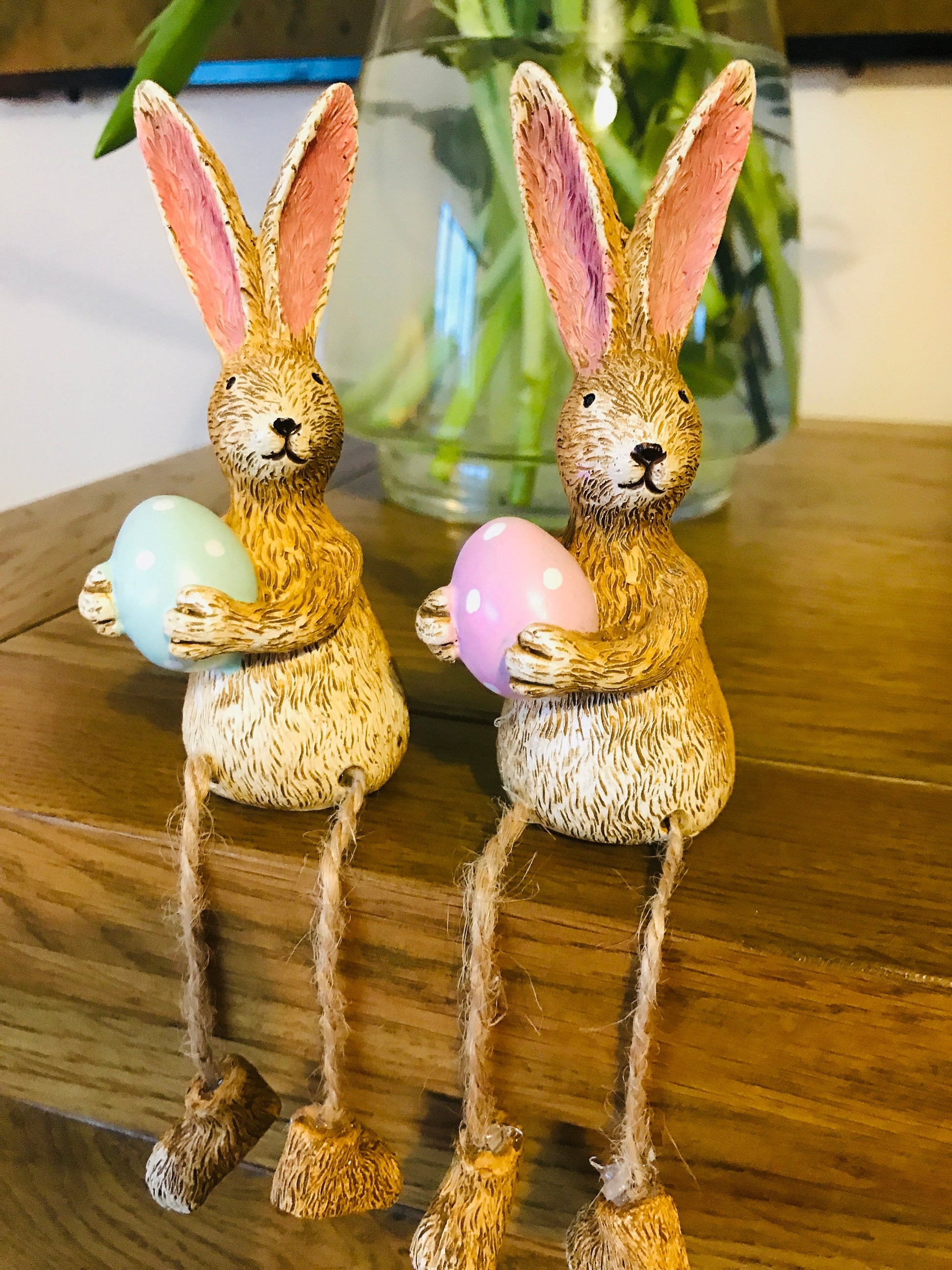 Hand-finished shelf sitting polyresin rabbit ornament with dangling jute legs and polka dot egg. Available with either  pink or green dotty eggs. Perfect Easter rabbit shelf decoration, birthday gift, or home décor accessory. Cute animal figurine for rabbit lovers, Easter decorations, new home presents, or seasonal mantel styling.