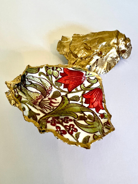Handmade Dorset oyster shell ring dish featuring William Morris Golden Lily floral artwork in green, red and gold tones. Natural oyster shell trinket dish with pearlescent interior, hand-finished liquid gold leaf edging and glossy resin coating. Decorative jewellery holder and coastal heritage gift inspired by classic William Morris interiors and Arts and Crafts design.
