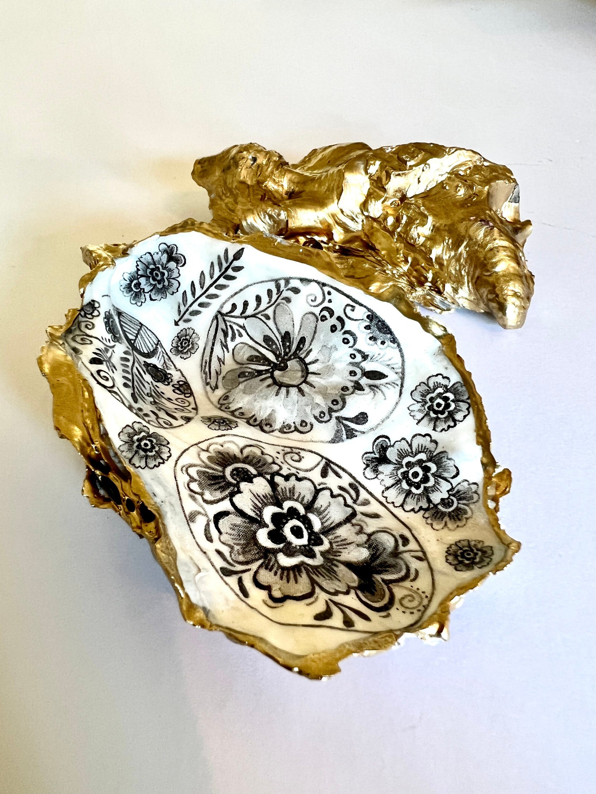 Handmade Dorset oyster shell dish featuring a decorative grey eggs design. Each oyster shell is finished with liquid gold leaf edging and reverse, sealed with crystal-clear resin for a glossy, durable shine. Unique and symbolic, the egg represents new life, fertility, hope, and luck, making this piece a thoughtful and meaningful gift. Ideal as a jewellery dish, oyster ring holder, trinket tray, or keepsake ornament. A coastal-inspired handmade gift for anniversaries, Easter, or Christmas.