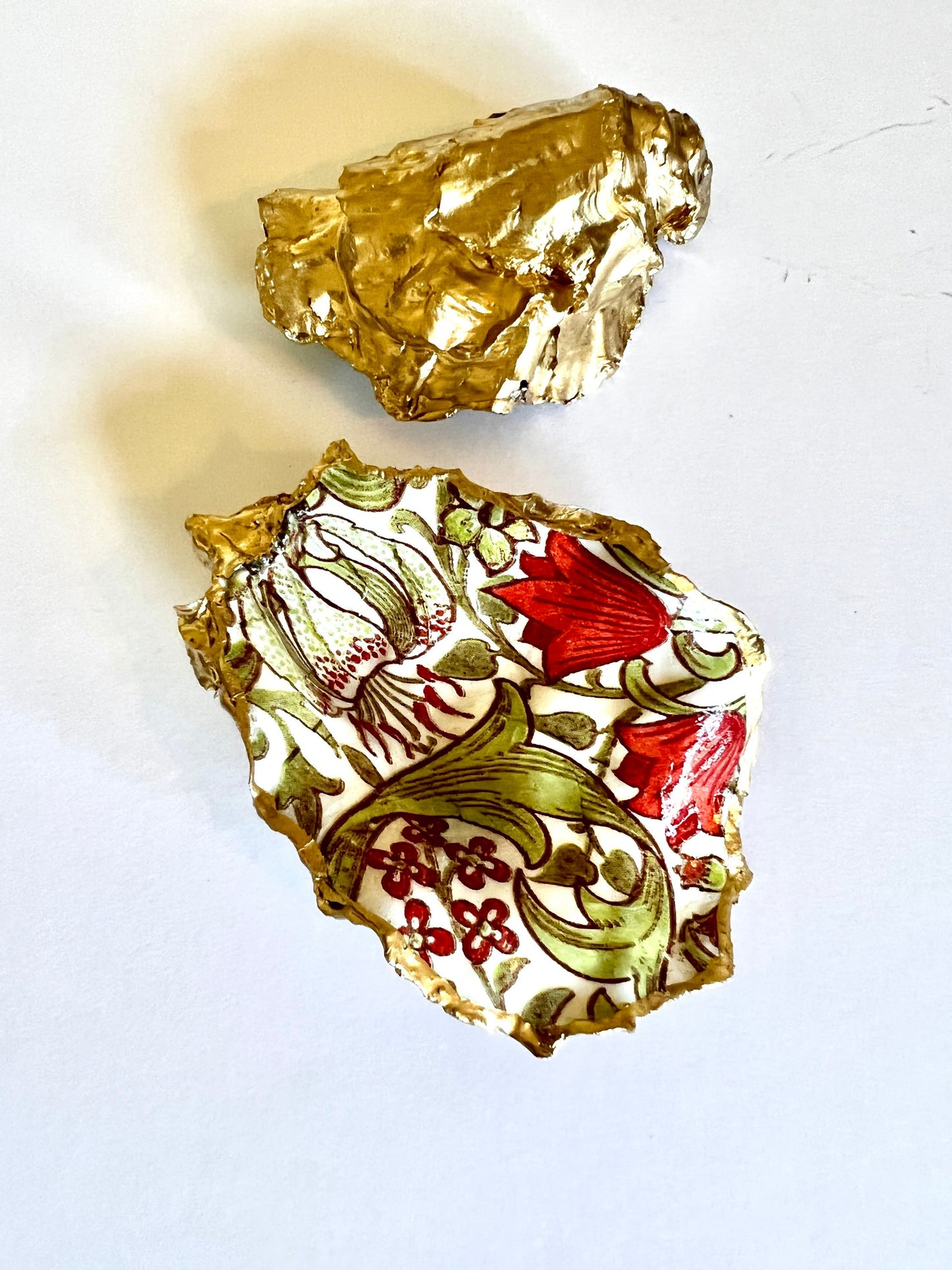 Handmade Dorset oyster shell ring dish featuring William Morris Golden Lily floral artwork in green, red and gold tones. Natural oyster shell trinket dish with pearlescent interior, hand-finished liquid gold leaf edging and glossy resin coating. Decorative jewellery holder and coastal heritage gift inspired by classic William Morris interiors and Arts and Crafts design.