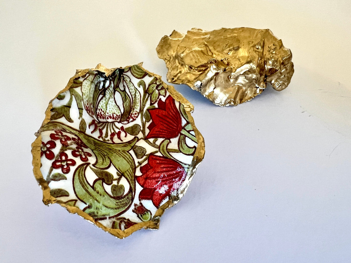 Handmade Dorset oyster shell ring dish featuring William Morris Golden Lily floral artwork in green, red and gold tones. Natural oyster shell trinket dish with pearlescent interior, hand-finished liquid gold leaf edging and glossy resin coating. Decorative jewellery holder and coastal heritage gift inspired by classic William Morris interiors and Arts and Crafts design.