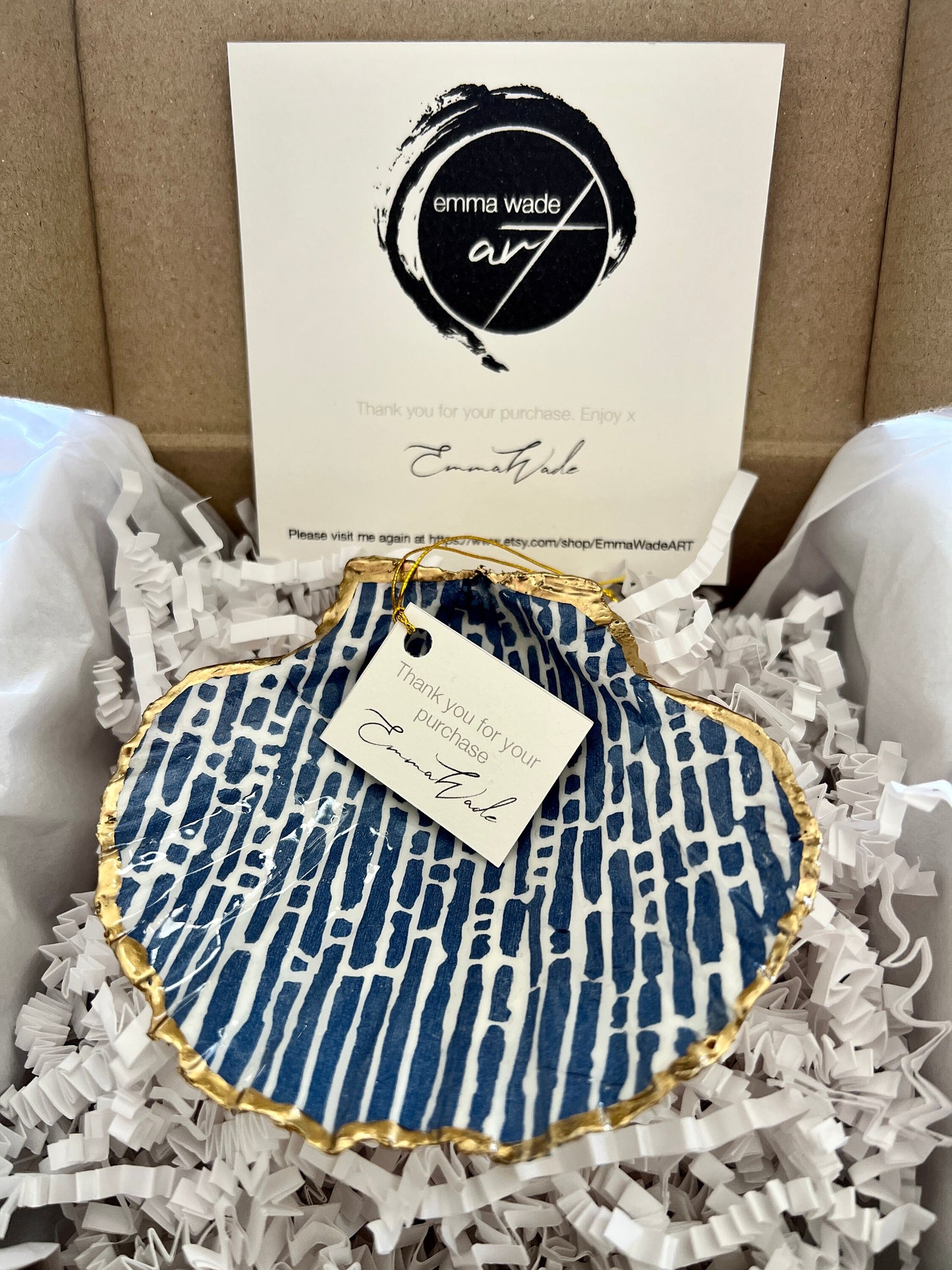 Handmade blue and white scallop shell trinket dish with gold leaf edging, crafted from a genuine Dorset shell and sealed with glossy resin. Coastal ring dish and jewellery holder featuring elegant blue line design, displayed in gift packaging. Artisan shell decor handmade in Surrey, perfect for coastal home styling, wedding gifts or nautical themed interiors.