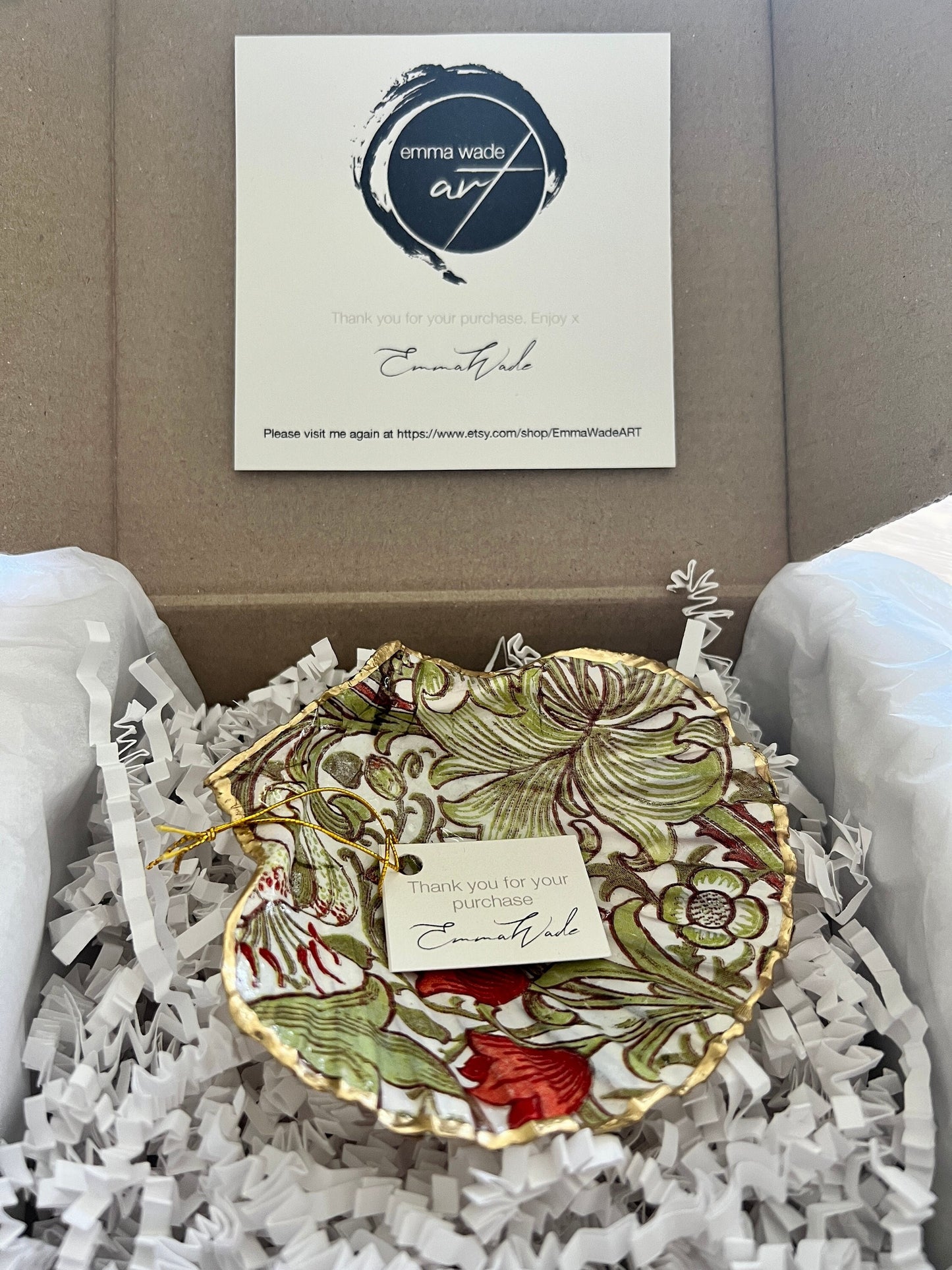 Handcrafted William Morris Golden Lily scallop shell ring holder featuring an elegant botanical floral pattern in green, cream and muted red tones. Decorative Dorset shell trinket dish finished with hand-painted gold leaf edging and sealed in glossy crystal resin for a luxurious shine. Coastal inspired jewellery tray and bedside catchall perfect for rings, earrings and keepsakes. Botanical shell decor for elegant interiors, cottage style homes, thoughtful handmade gifting.