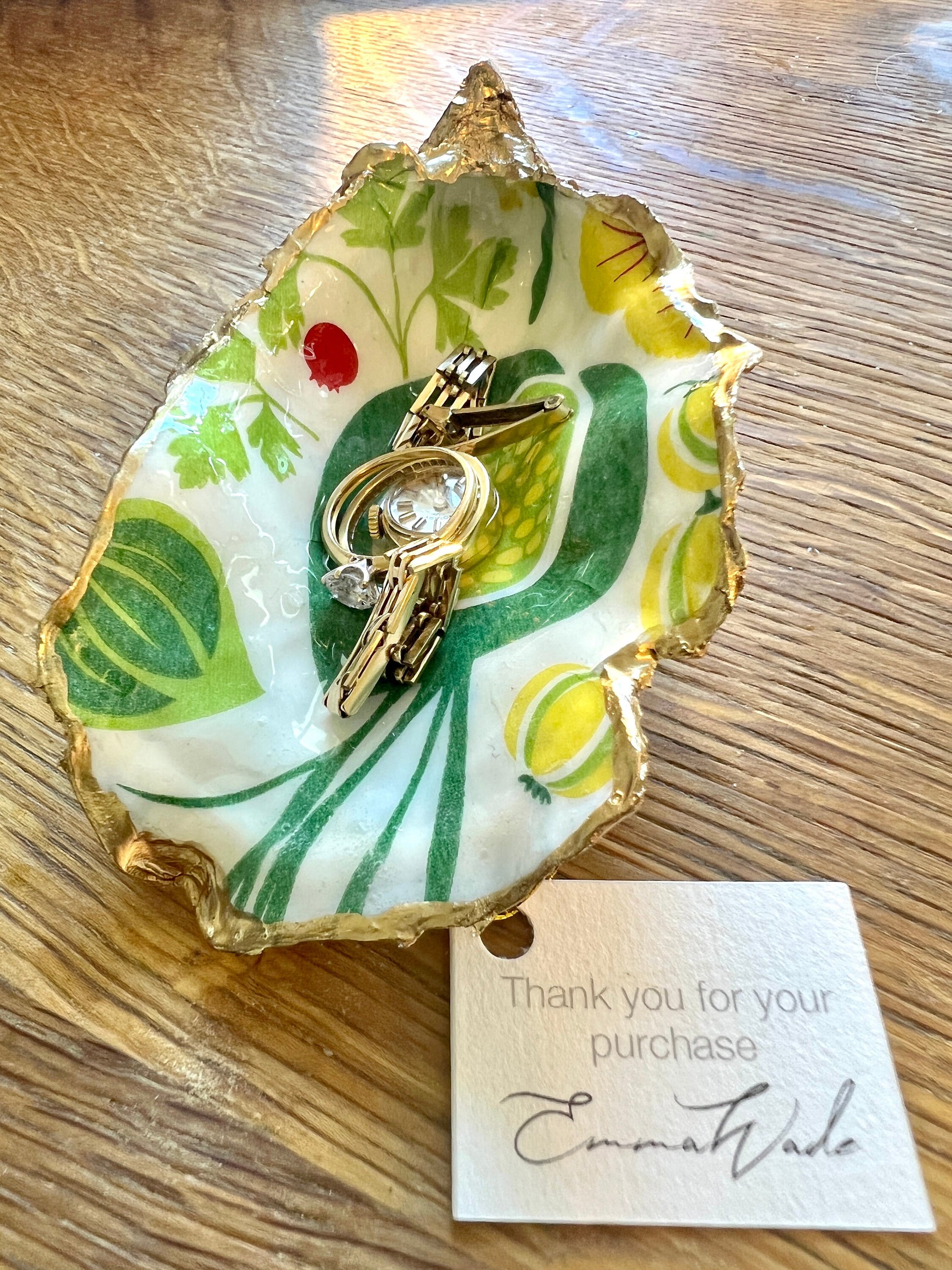 Handmade Dorset oyster shell trinket dish featuring colourful garden fruit artwork in green, yellow, and red tones with hand-gilded gold leaf edging and glossy resin finish. Coastal jewellery holder and botanical home décor gift.