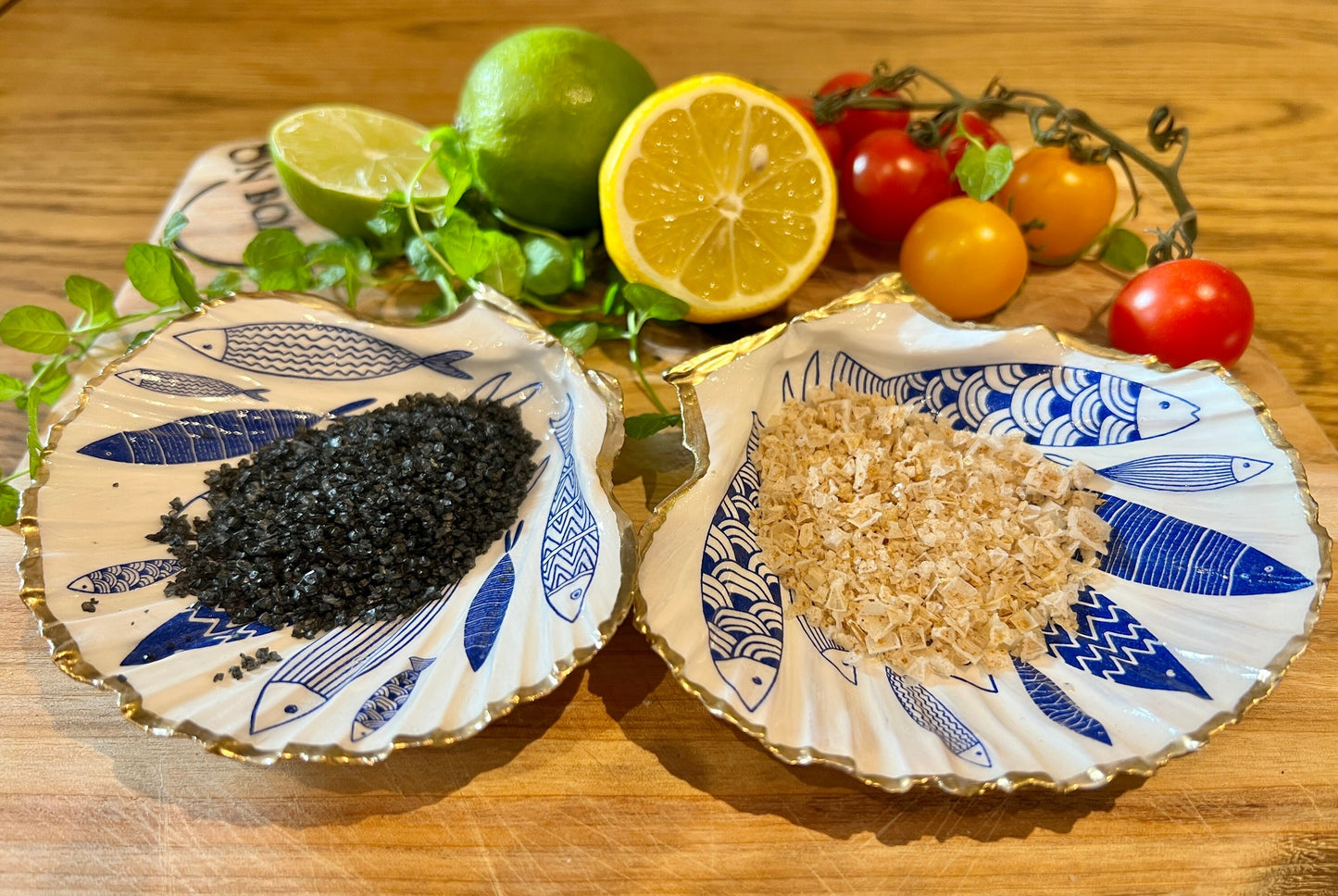 Handmade Dorset scallop shell trinket dishes featuring elegant blue fish illustrations with hand-painted gold leaf edging and glossy crystal clear resin. Coastal nautical jewellery dishes inspired by Scandinavian ocean decor, styled on a neutral background with detailed blue fish artwork and luxurious gilded edges.