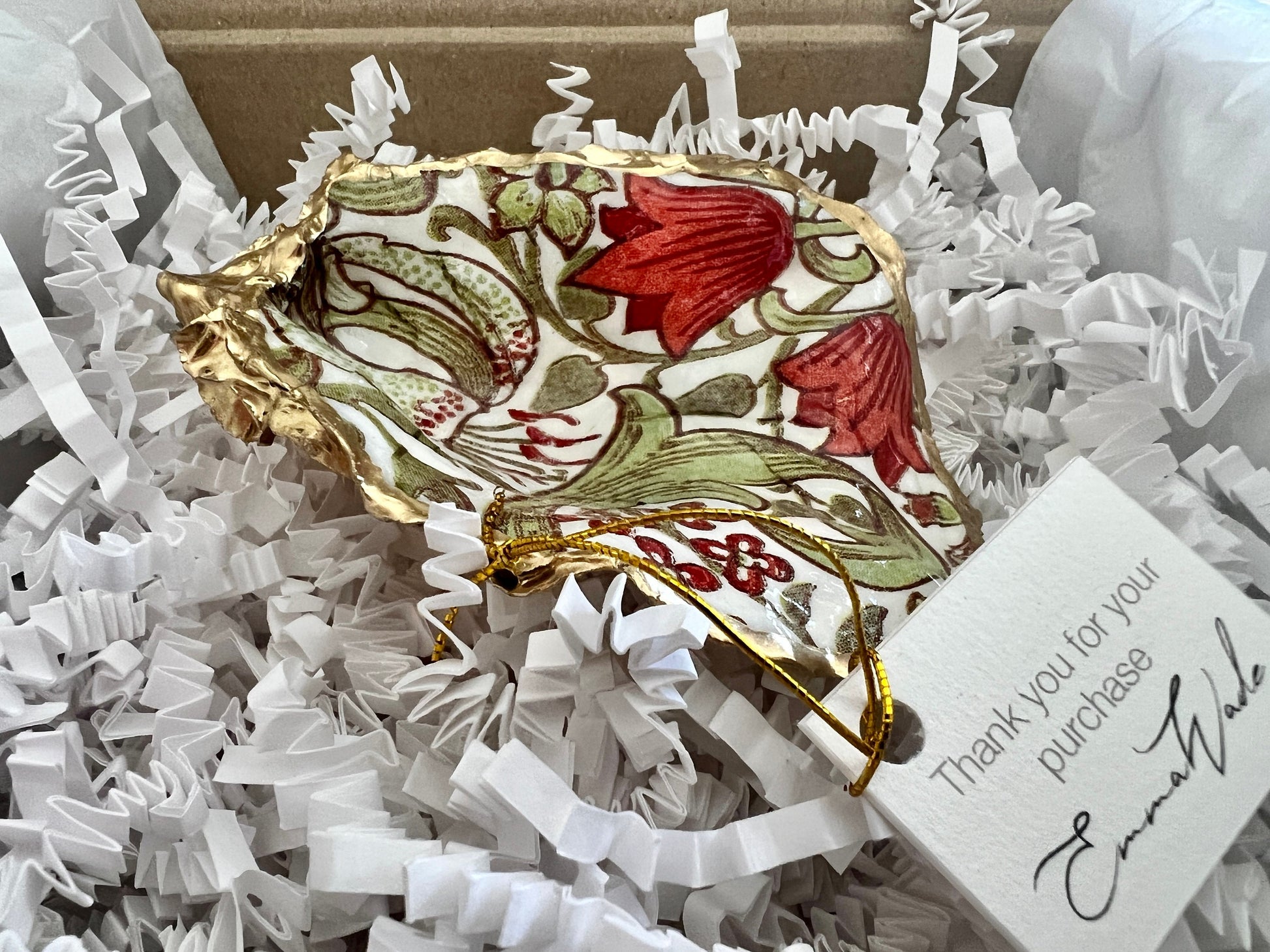 Handmade Dorset oyster shell ring dish featuring William Morris Golden Lily floral artwork in green, red and gold tones. Natural oyster shell trinket dish with pearlescent interior, hand-finished liquid gold leaf edging and glossy resin coating. Decorative jewellery holder and coastal heritage gift inspired by classic William Morris interiors and Arts and Crafts design.