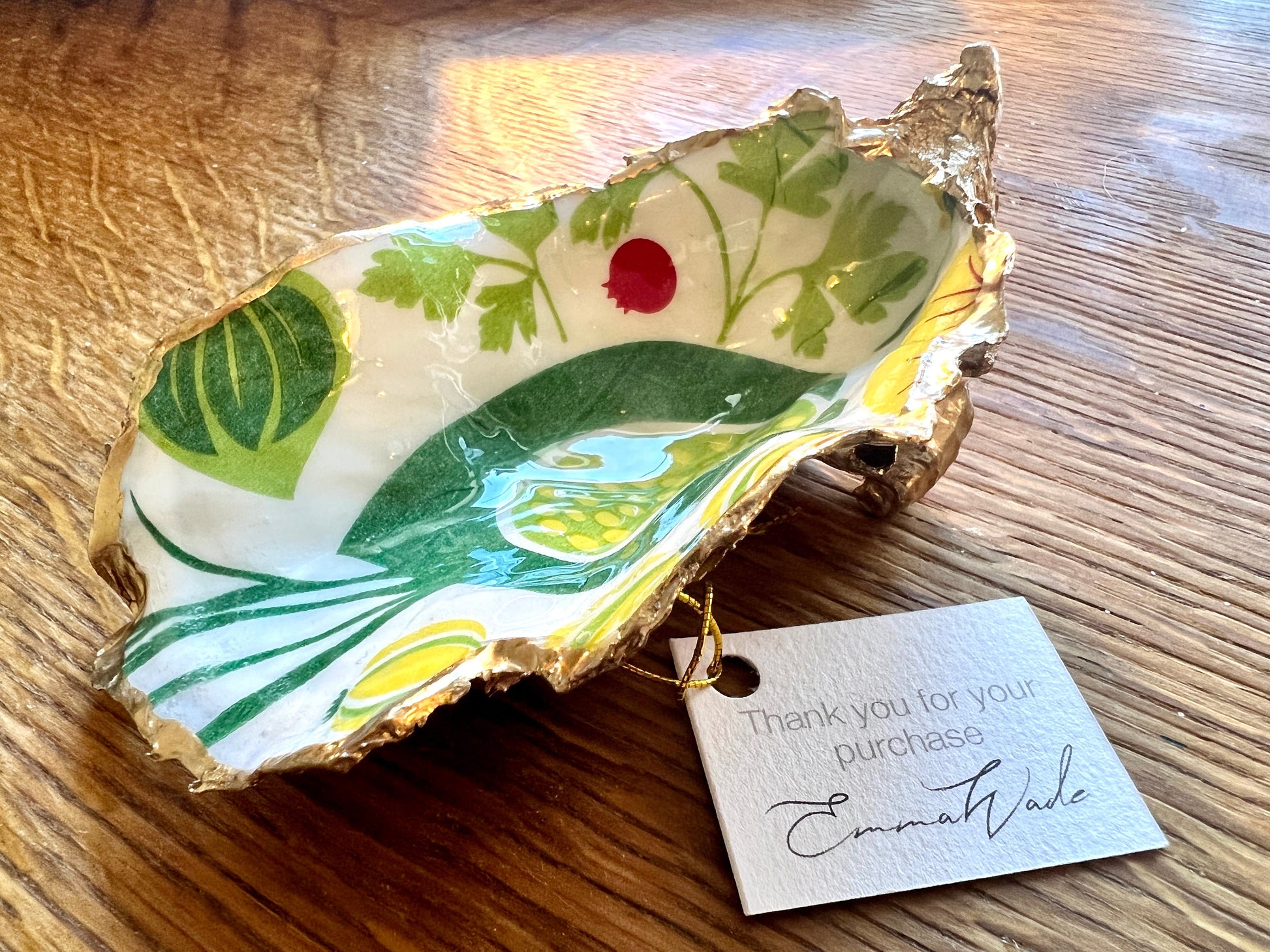 Oyster shell trinket dish with a green, red, and yellow vegetable design, edged with liquid gold leaf and sealed with glossy resin. Handmade from Dorset shells, each dish is one of a kind. A unique oyster ring dish, shell jewellery holder, or trinket tray for storing rings, earrings, cufflinks, or keepsakes. Perfect as coastal decor or a thoughtful handmade gift for weddings, anniversaries, birthdays, Mother’s Day, or Christmas. A colourful nature-inspired jewellery organiser.