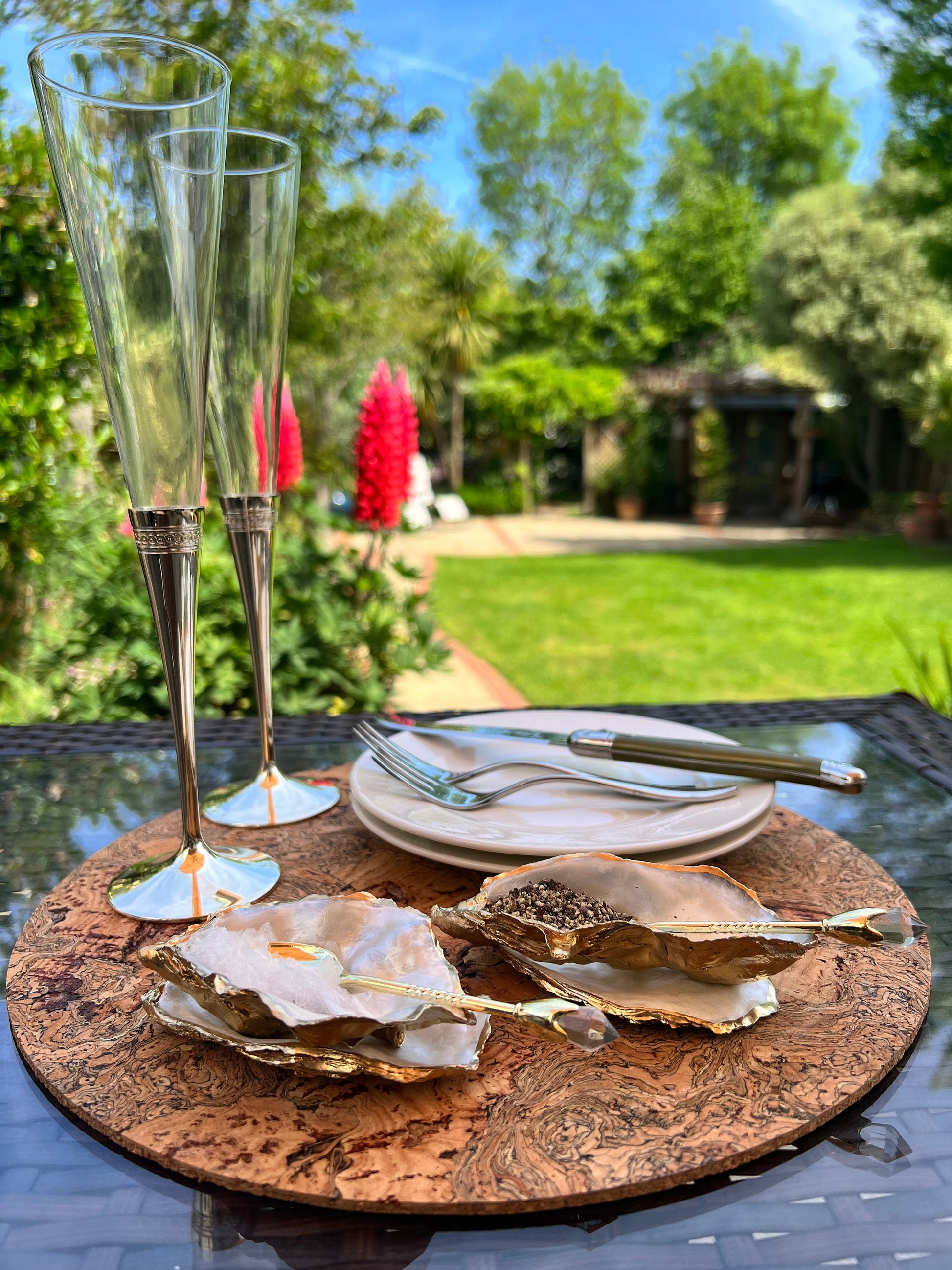 Handmade gold leaf oyster shell salt cellar set with pearl interiors and matching spoons. Coastal pinch pots made from Dorset oyster shells, sealed with glossy resin and finished with gilded edges. Luxury tableware set photographed on a light background, showing two shell salt dishes and decorative spoons, perfect for serving salt or spices at the table.