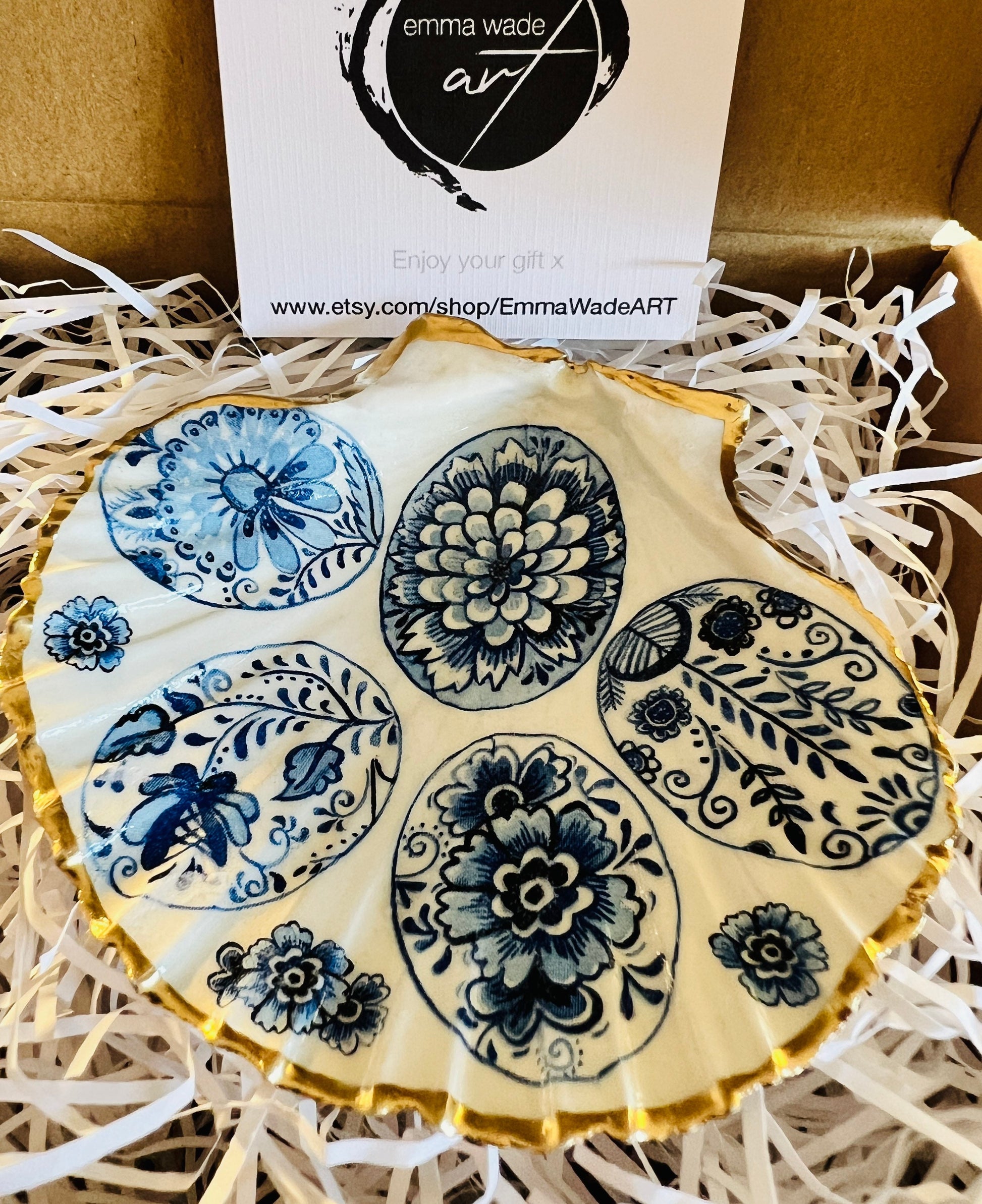 Handmade Dorset scallop shell trinket dishes featuring vintage inspired blue and white egg artwork with hand-painted gold leaf edging and glossy crystal clear resin. Elegant coastal jewellery dishes styled with Nordic and Scandinavian inspired porcelain patterns, photographed on soft neutral backgrounds with luxurious gilded detailing.