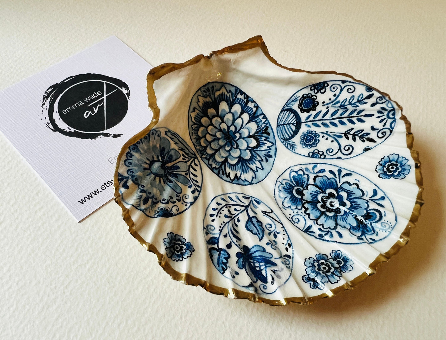 Handmade Dorset scallop shell trinket dishes featuring vintage inspired blue and white egg artwork with hand-painted gold leaf edging and glossy crystal clear resin. Elegant coastal jewellery dishes styled with Nordic and Scandinavian inspired porcelain patterns, photographed on soft neutral backgrounds with luxurious gilded detailing.