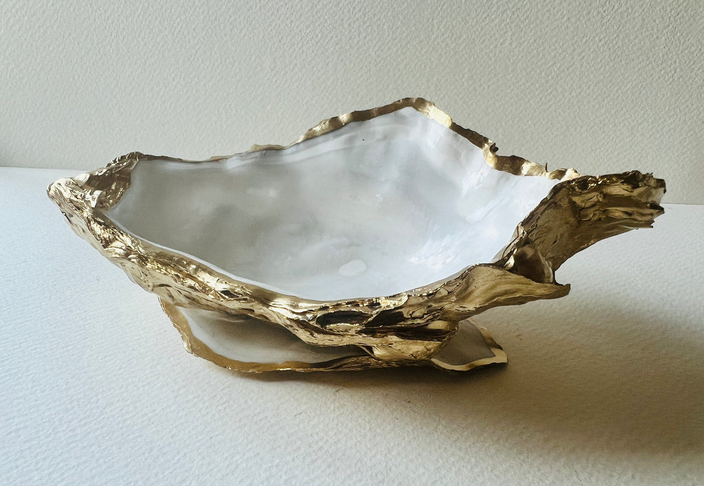 Extra large Dorset oyster shell serving dish set with natural pearl interior and hand-applied gold leaf edging, featuring a cupped XL oyster shell with matching flat shell base. Luxury coastal home décor ideal as a sugar dish, serving bowl, coffee station accessory, or elegant host gift. Handmade using sustainably sourced UK oyster shells and finished with glossy resin and optional gold serving accessories.