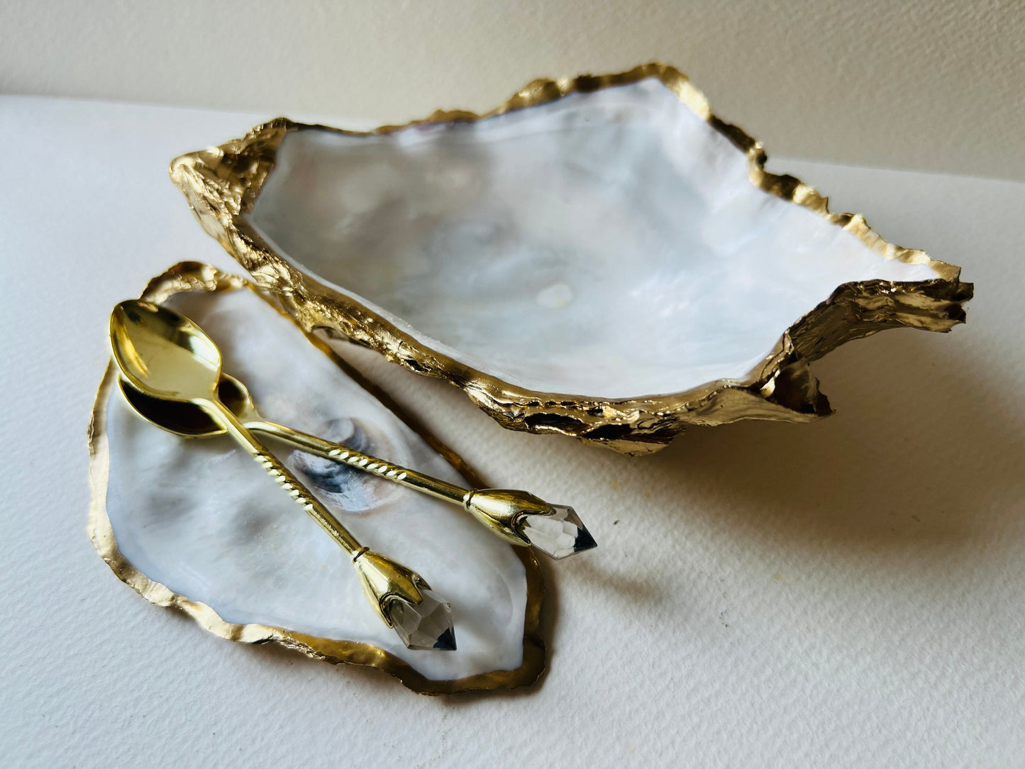 Extra large Dorset oyster shell serving dish set with natural pearl interior and hand-applied gold leaf edging, featuring a cupped XL oyster shell with matching flat shell base. Luxury coastal home décor ideal as a sugar dish, serving bowl, coffee station accessory, or elegant host gift. Handmade using sustainably sourced UK oyster shells and finished with glossy resin and optional gold serving accessories.