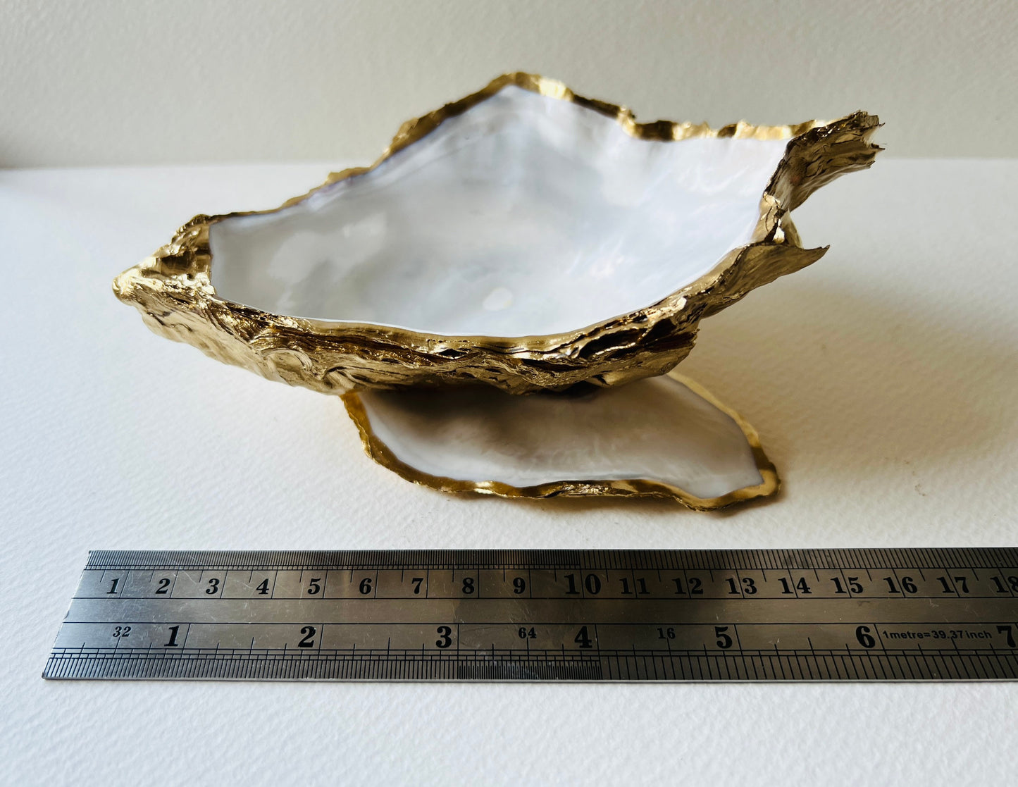 Extra large Dorset oyster shell serving dish set with natural pearl interior and hand-applied gold leaf edging, featuring a cupped XL oyster shell with matching flat shell base. Luxury coastal home décor ideal as a sugar dish, serving bowl, coffee station accessory, or elegant host gift. Handmade using sustainably sourced UK oyster shells and finished with glossy resin and optional gold serving accessories.