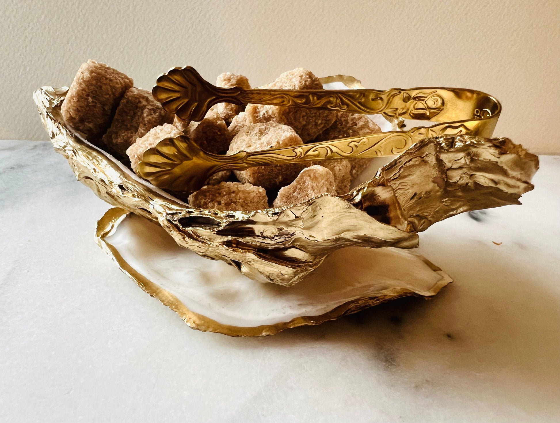 Extra large Dorset oyster shell serving dish set with natural pearl interior and hand-applied gold leaf edging, featuring a cupped XL oyster shell with matching flat shell base. Luxury coastal home décor ideal as a sugar dish, serving bowl, coffee station accessory, or elegant host gift. Handmade using sustainably sourced UK oyster shells and finished with glossy resin and optional gold serving accessories.