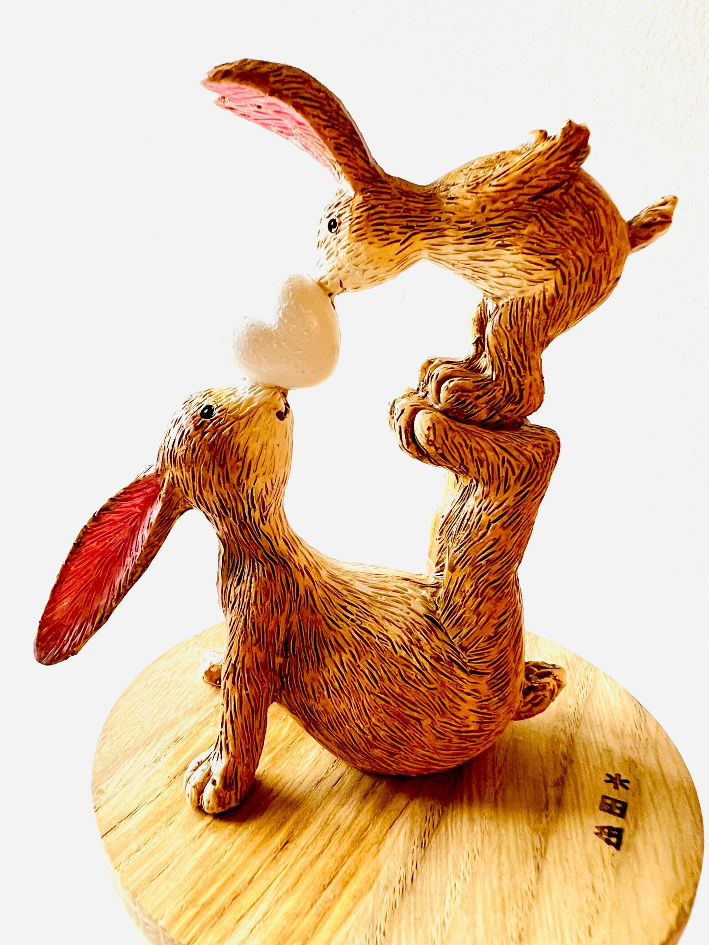 Hand finished polyresin bunny ornament showing mother rabbit balancing baby bunny on her feet while holding a small heart, rustic brown textured finish with pink inner ears.