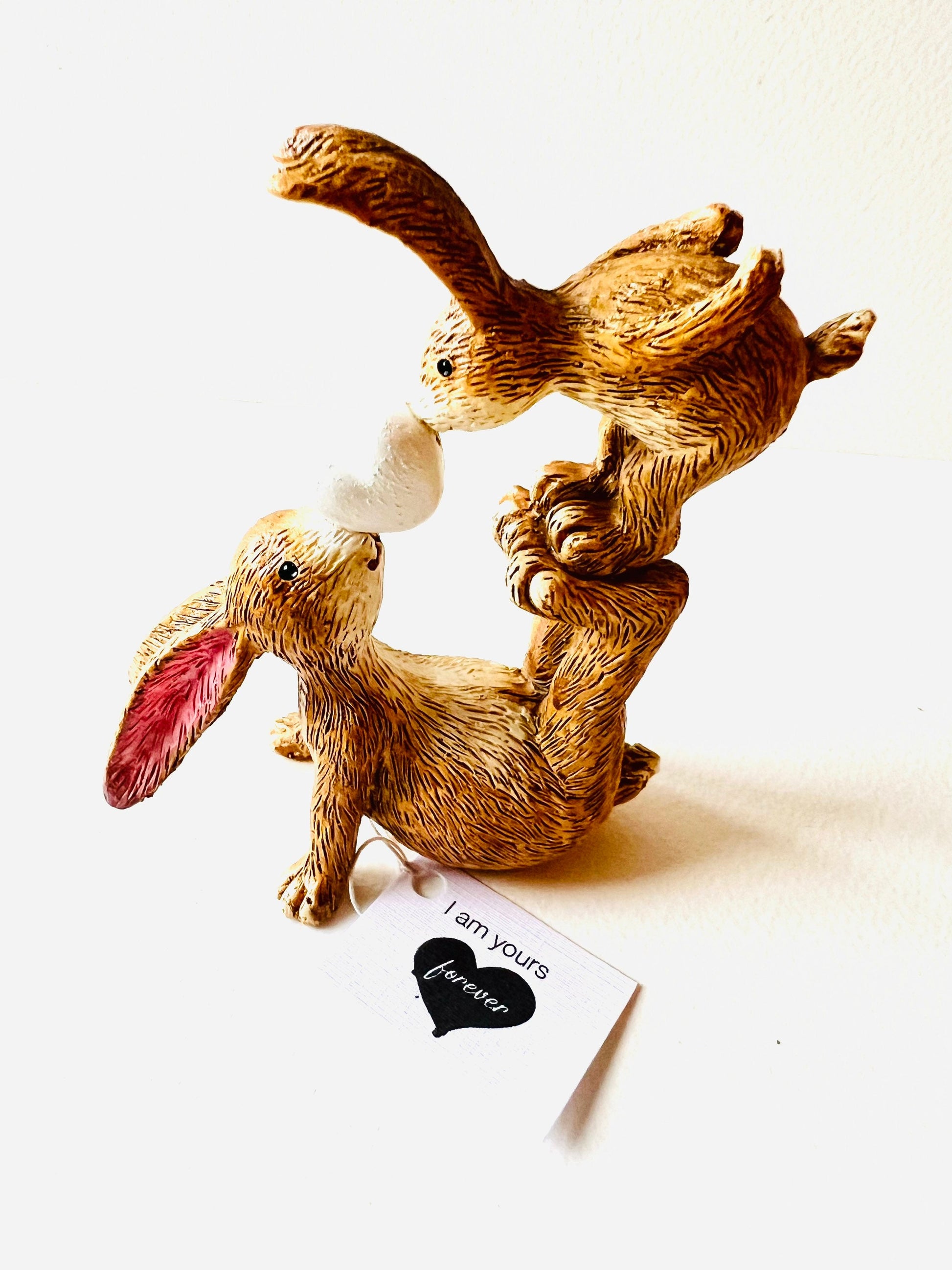 Hand finished polyresin bunny ornament showing mother rabbit balancing baby bunny on her feet while holding a small heart, rustic brown textured finish with pink inner ears.