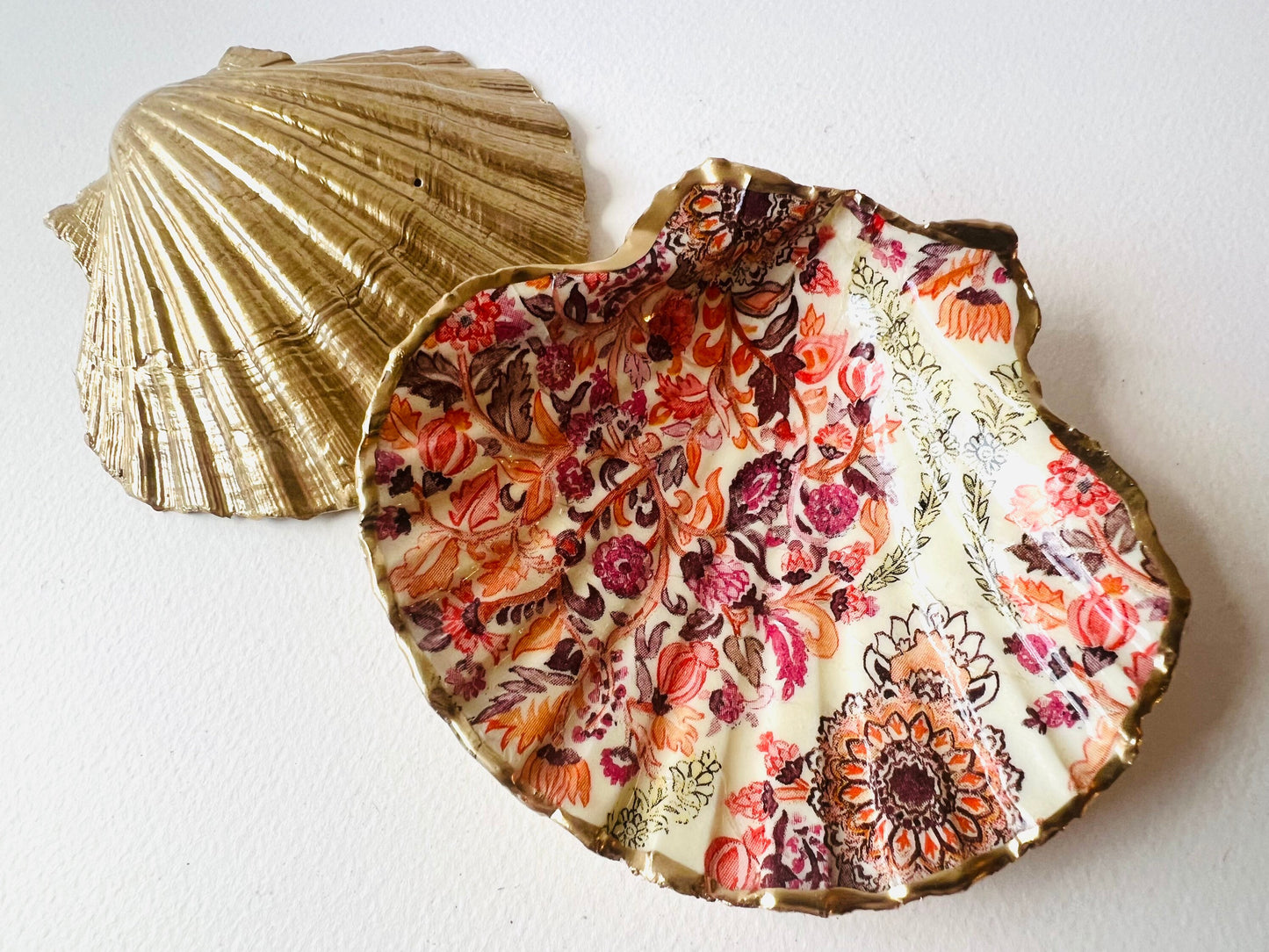Handmade Dorset scallop shell trinket dish featuring a William Morris inspired pink floral botanical design in coral, berry and soft gold tones. Decorative jewellery holder finished with hand-applied liquid gold leaf edging and glossy resin. Heritage style coastal décor shell dish with romantic English country house aesthetic, styled as a ring holder and elegant vanity accessory.