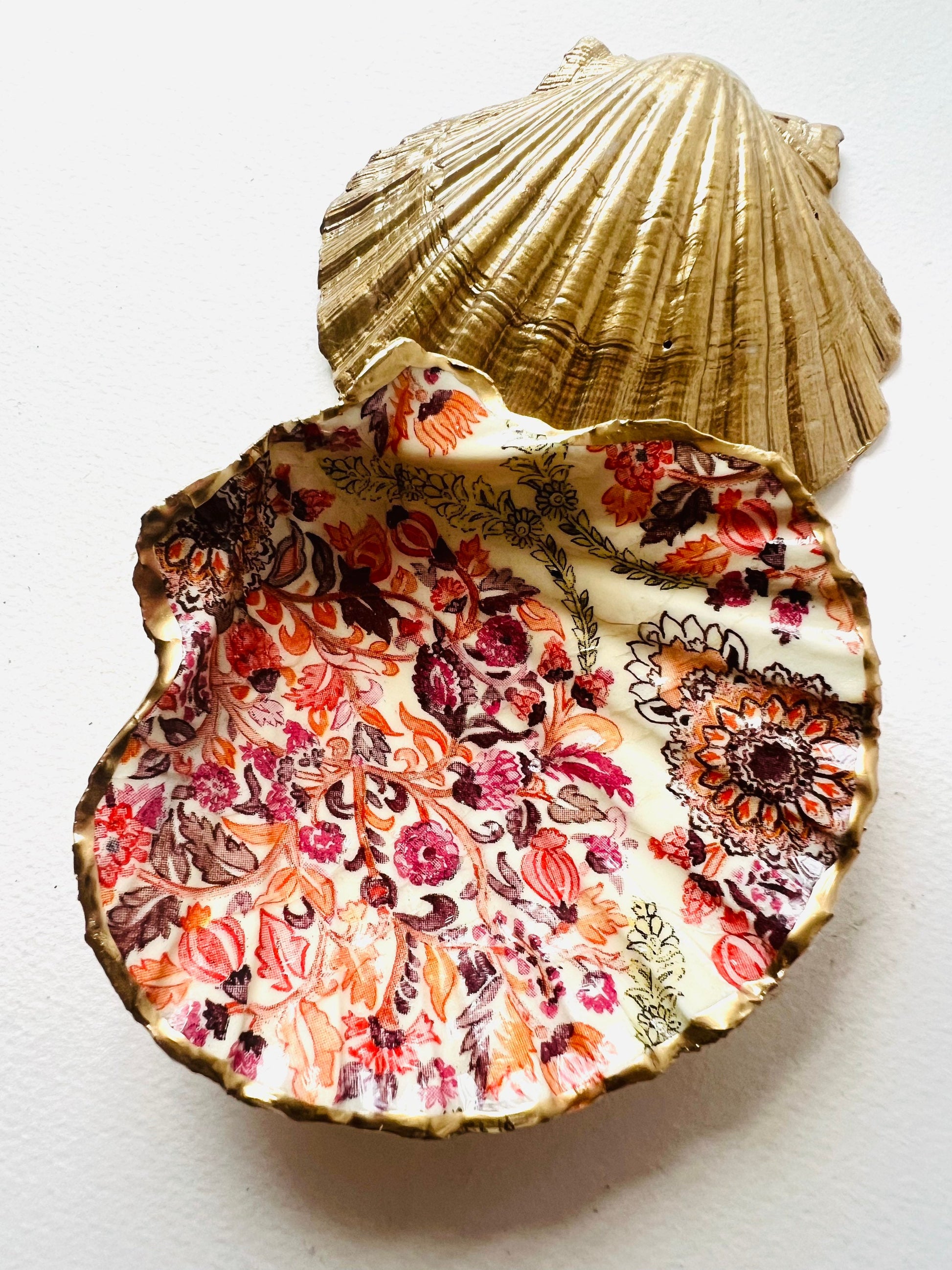 Handmade Dorset scallop shell trinket dish featuring a William Morris inspired pink floral botanical design in coral, berry and soft gold tones. Decorative jewellery holder finished with hand-applied liquid gold leaf edging and glossy resin. Heritage style coastal décor shell dish with romantic English country house aesthetic, styled as a ring holder and elegant vanity accessory.