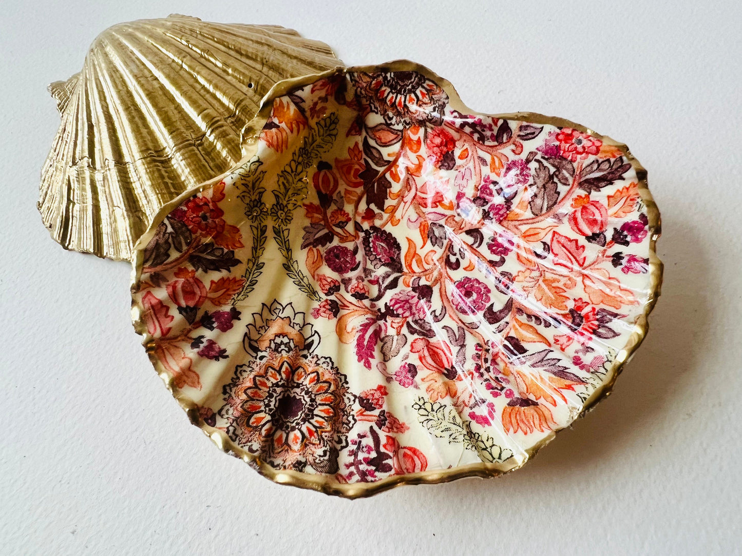 Handmade Dorset scallop shell trinket dish featuring a William Morris inspired pink floral botanical design in coral, berry and soft gold tones. Decorative jewellery holder finished with hand-applied liquid gold leaf edging and glossy resin. Heritage style coastal décor shell dish with romantic English country house aesthetic, styled as a ring holder and elegant vanity accessory.