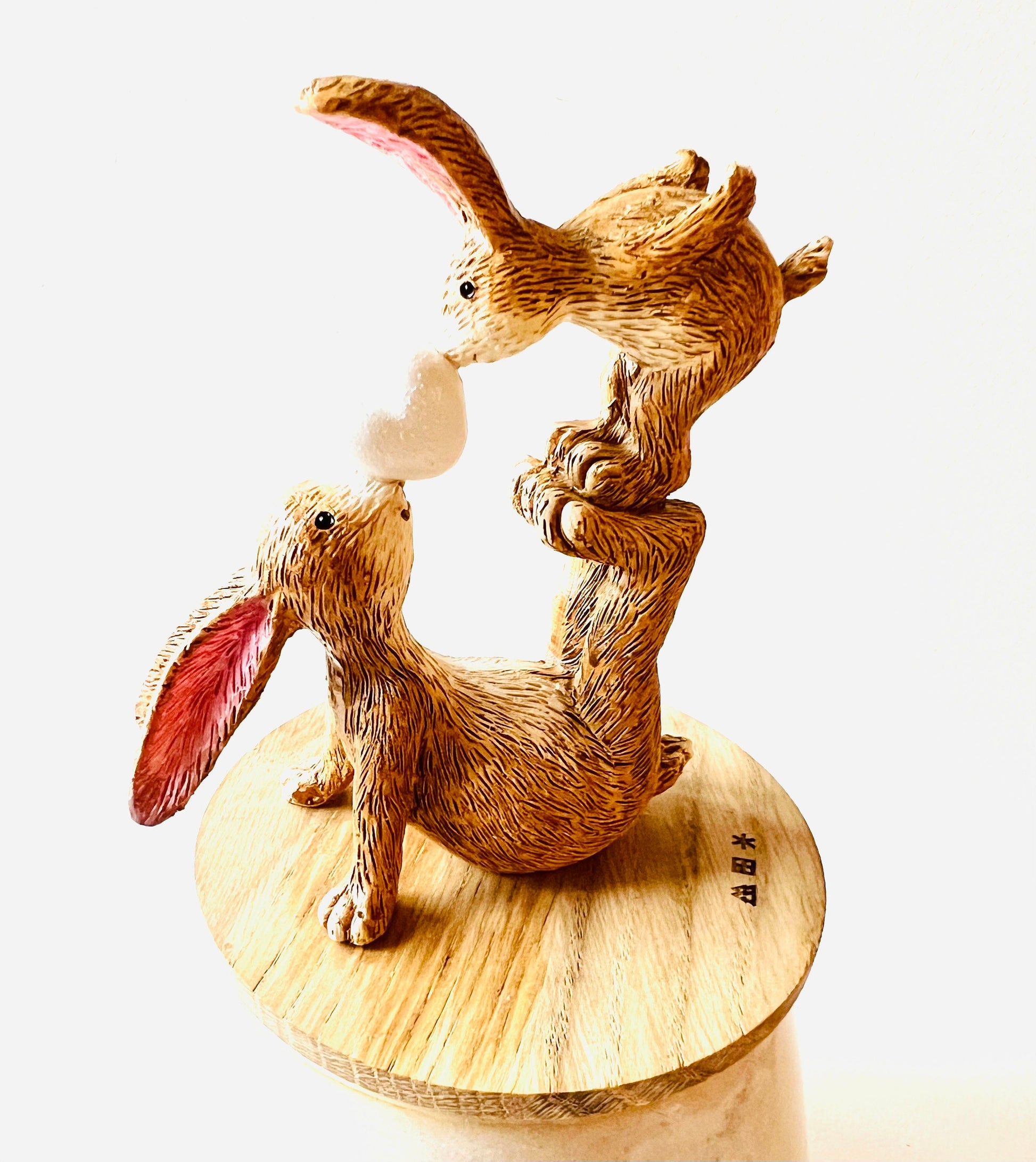 Hand finished polyresin bunny ornament showing mother rabbit balancing baby bunny on her feet while holding a small heart, rustic brown textured finish with pink inner ears.