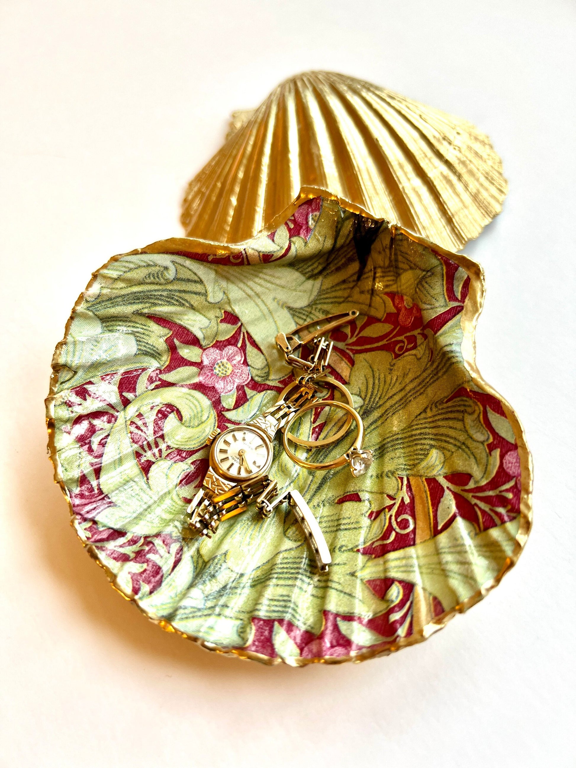 Handmade Dorset scallop shell trinket dish featuring William Morris Granville Bordeaux pattern, finished with real gold leaf edging and a glossy resin coating. A sustainable coastal jewellery dish and ring holder, individually handcrafted in the UK. Ideal as a unique gift for her, wedding or anniversary present, or elegant home décor accent inspired by nature and classic Arts and Crafts design.