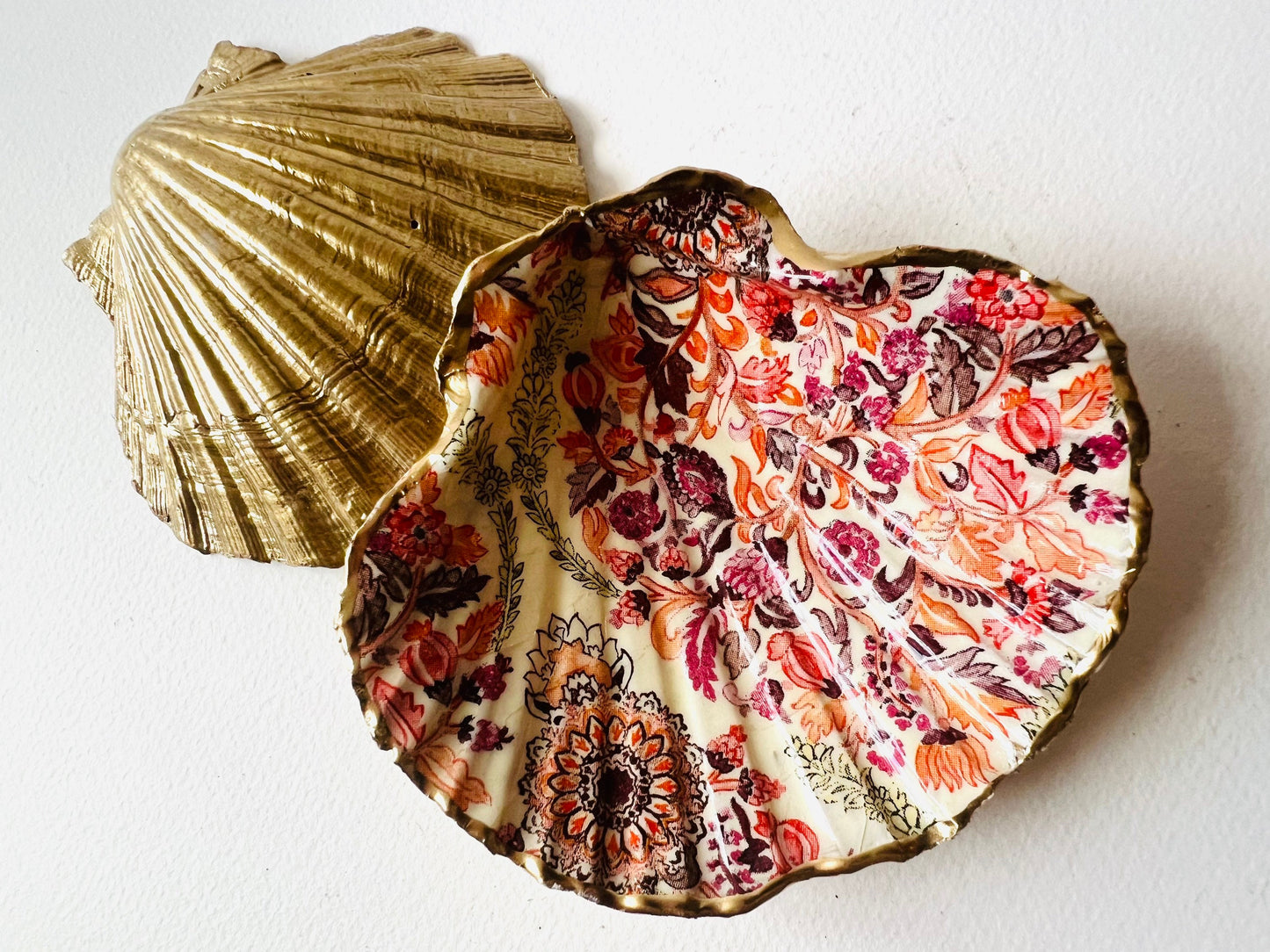 Handmade Dorset scallop shell trinket dish featuring a William Morris inspired pink floral botanical design in coral, berry and soft gold tones. Decorative jewellery holder finished with hand-applied liquid gold leaf edging and glossy resin. Heritage style coastal décor shell dish with romantic English country house aesthetic, styled as a ring holder and elegant vanity accessory.