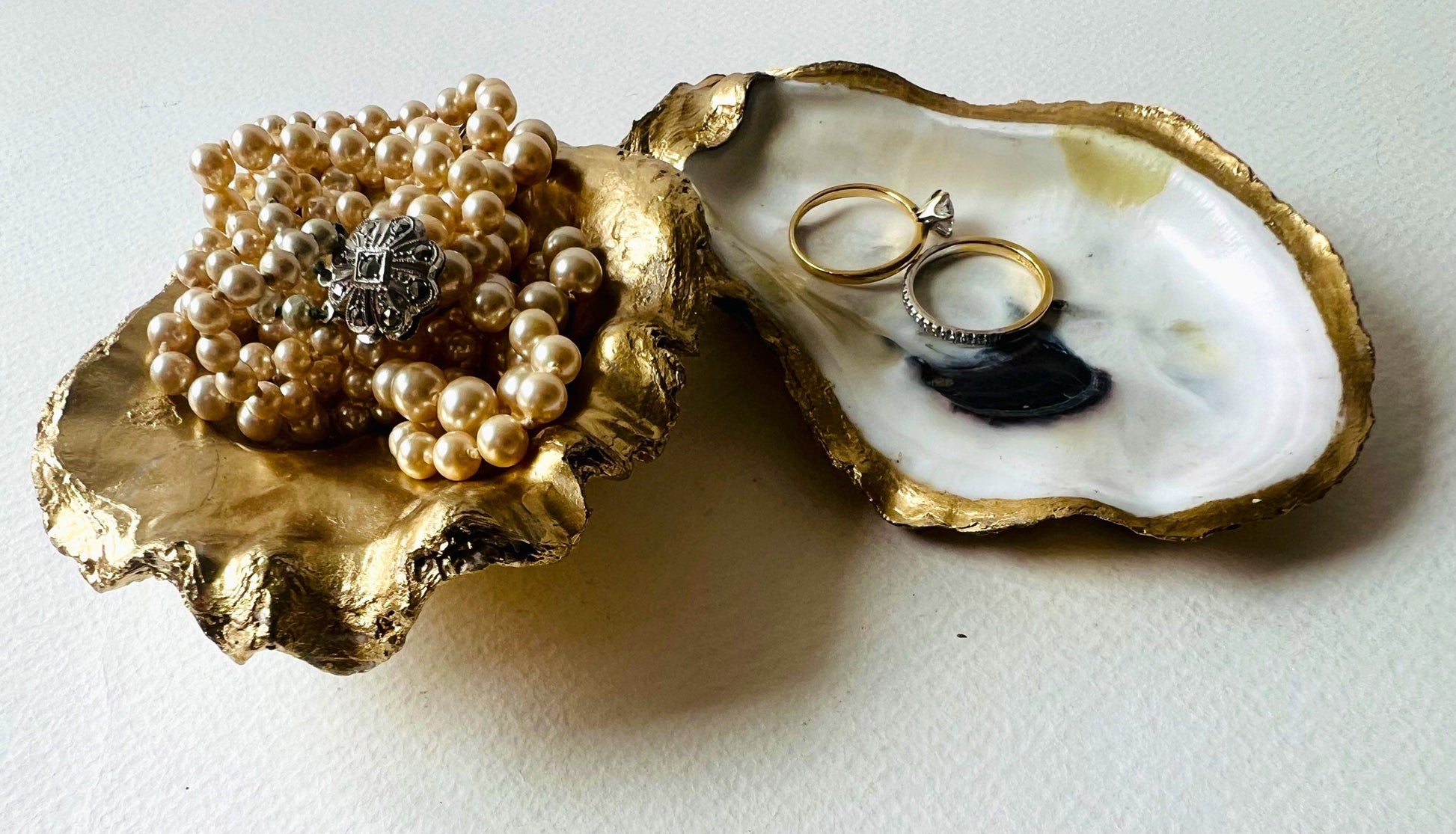 Gold leaf oyster shell jewellery dish with pearl finish, handmade Dorset oyster shell ring holder and trinket dish. Matching flat oyster base with gilded edges, eco-friendly coastal home decor. Unique oyster shell gift, wedding ring box, anniversary present, salt pinch pot, nautical bathroom accessory. Handcrafted shell ornament, sustainable oyster decor, handmade UK jewellery storage.