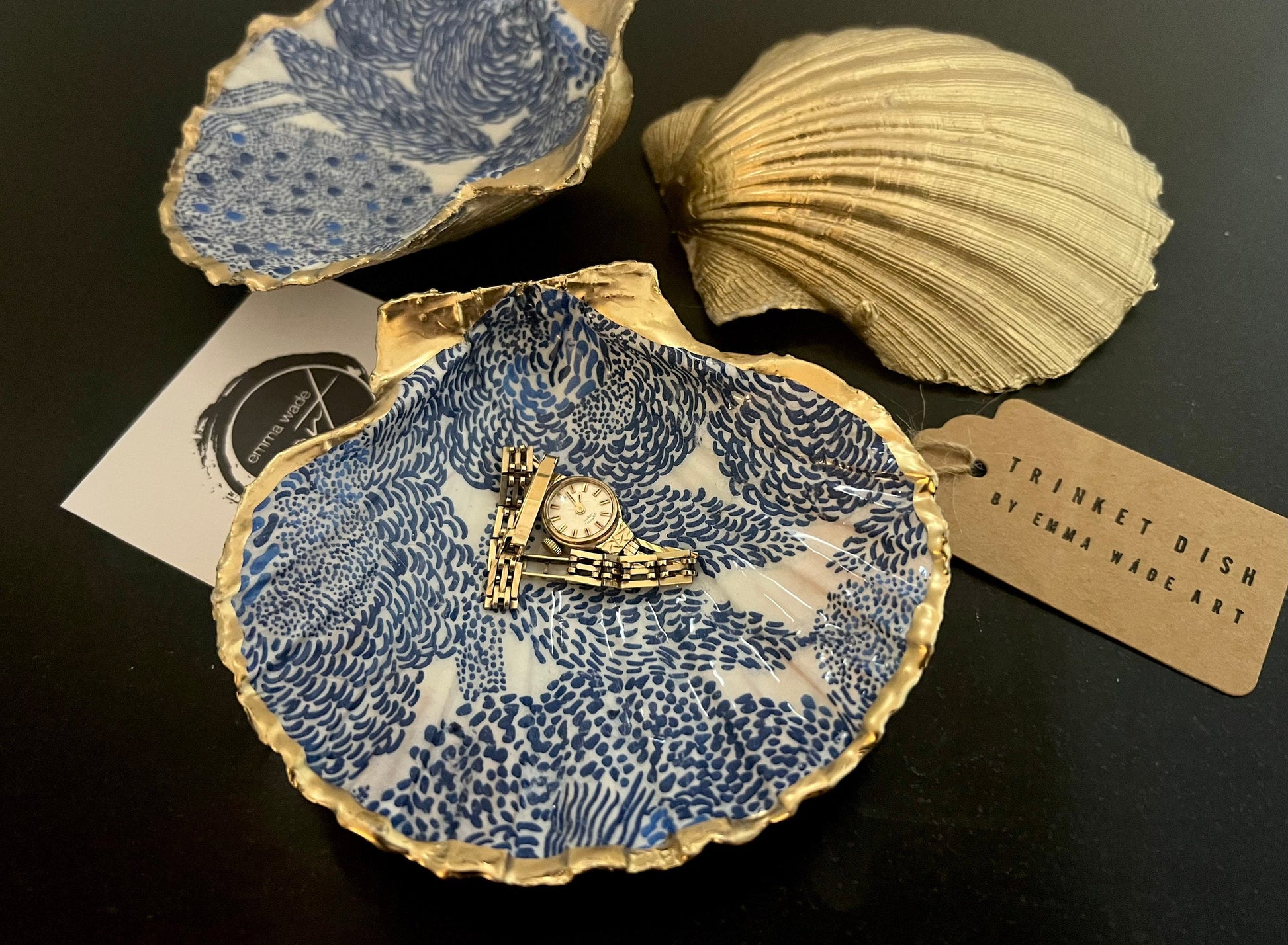 Marimekko inspired blue floral scallop shell trinket dish with hand-applied gold leaf edging and glossy resin finish. Natural Dorset shell jewellery holder featuring bold Scandinavian style botanical pattern. Decorative coastal ring dish styled on a marble surface, ideal as a bedside trinket bowl, host gift or luxury handmade home accent.