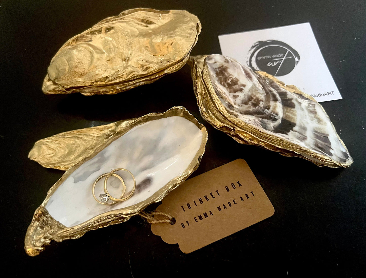 Luxury Dorset oyster shell ring and jewellery box with matching lid, finished with gold leaf detailing and glossy resin. 4 designs avaialble including natural oyster shell with gold rim and pearl interior, gold leaf shell with natural white interior, or gold leaf shell with decoupage interior. Shown holding rings on a light background, highlighting the natural shell shape and polished handcrafted coastal keepsake style. Ideal as an engagement ring box, wedding ring holder, or jewellery keepsake.