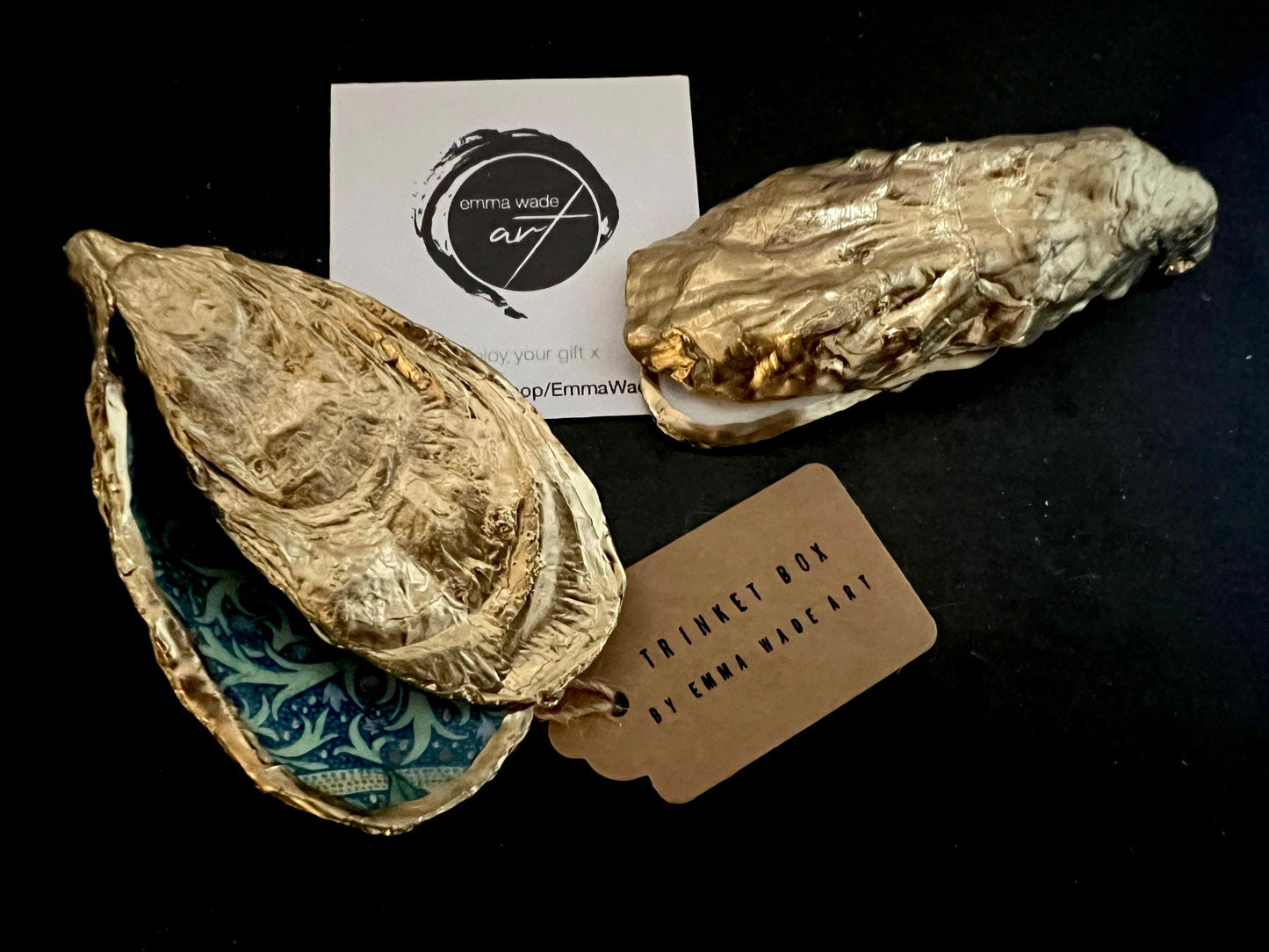Selection of Dorset oyster shell ring and jewellery boxes in three designs, including natural pearl interior, gold leaf exterior, and patterned decoupage interior. Handcrafted oyster shells with matching lids, shown on a dark background with rings and packaging, highlighting the different finishes, gilded edges, and polished resin surfaces. Coastal keepsake boxes designed to hold engagement rings, wedding rings, or small jewellery items.