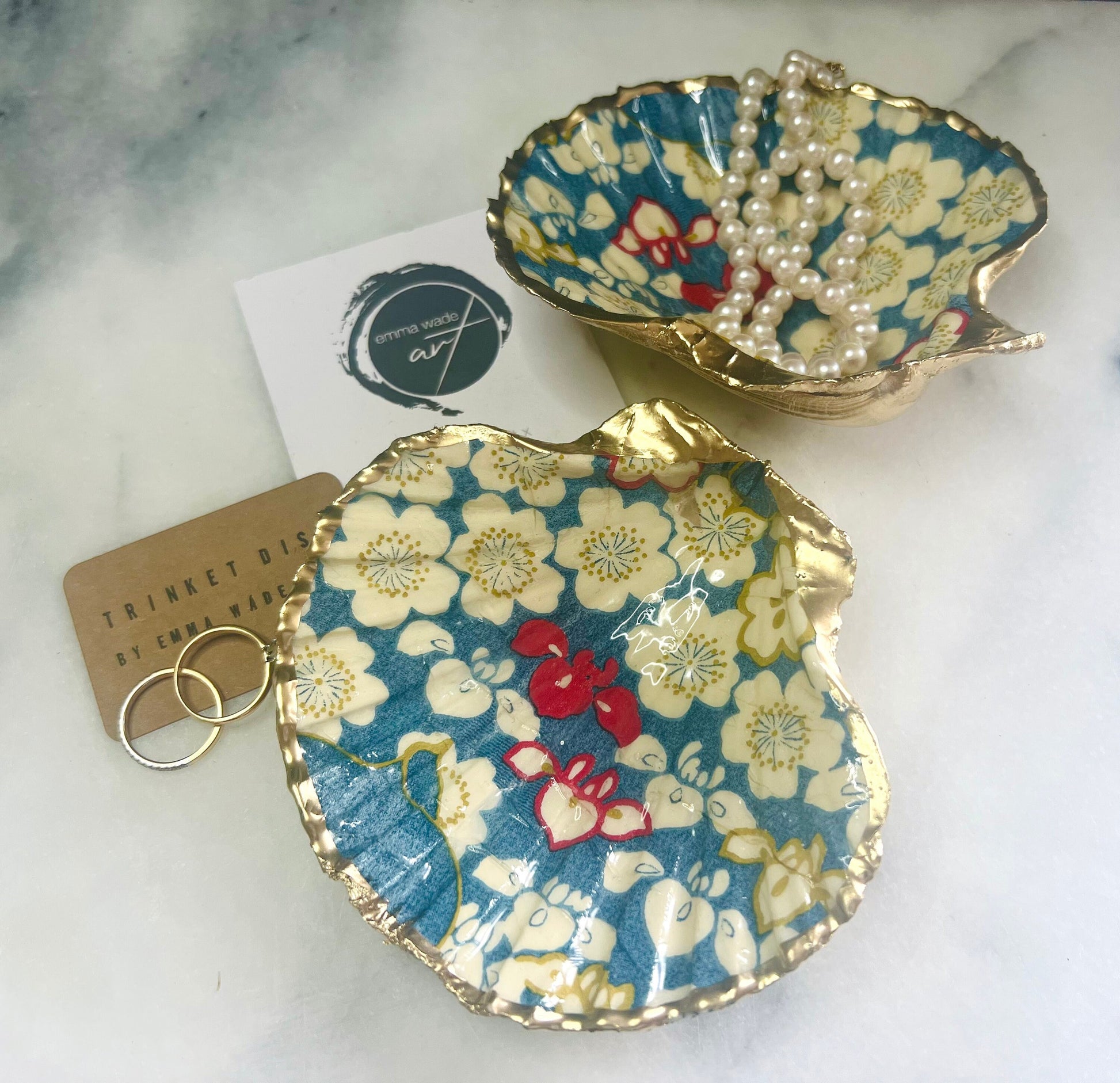 Japanese Sakura cherry blossom floral scallop shell trinket dish with blue, cream and red botanical flower design, hand finished with liquid gold leaf edging and glossy resin. Handmade coastal jewellery tray and ring dish inspired by Japanese floral art and Dorset coastal décor.