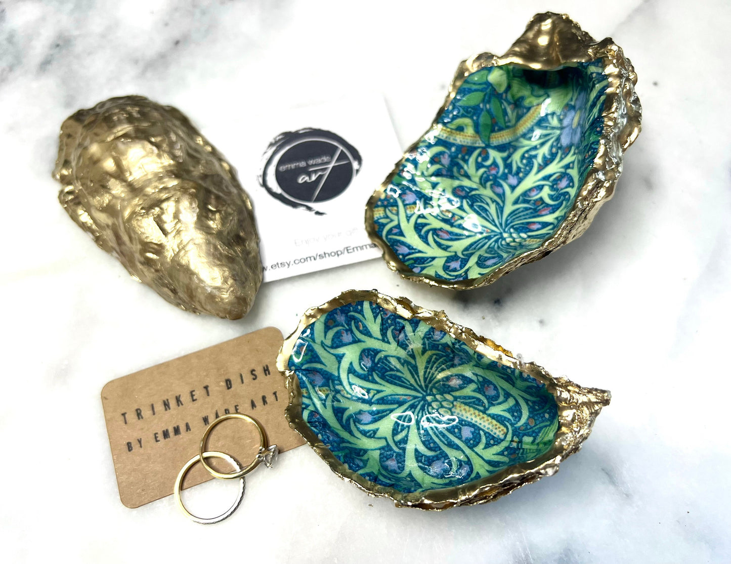 Handmade William Morris inspired oyster shell trinket dish in green and blue tones, finished with gold leaf and sealed with glossy resin. Coastal jewellery dish made from a Dorset oyster shell, featuring a seaweed decoupage design. Perfect for holding rings, earrings and small treasures. Decorative shell bowl photographed on a light background, showing the natural shell shape, detailed pattern and gilded edges.