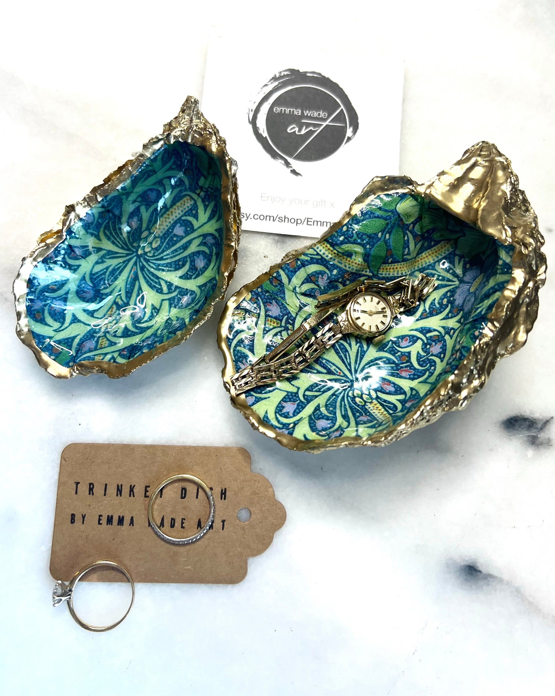 Handmade William Morris inspired oyster shell trinket dish in green and blue tones, finished with gold leaf and sealed with glossy resin. Coastal jewellery dish made from a Dorset oyster shell, featuring a seaweed decoupage design. Perfect for holding rings, earrings and small treasures. Decorative shell bowl photographed on a light background, showing the natural shell shape, detailed pattern and gilded edges.