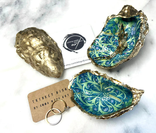 Handmade William Morris inspired oyster shell trinket dish in green and blue tones, finished with gold leaf and sealed with glossy resin. Coastal jewellery dish made from a Dorset oyster shell, featuring a seaweed decoupage design. Perfect for holding rings, earrings and small treasures. Decorative shell bowl photographed on a light background, showing the natural shell shape, detailed pattern and gilded edges.