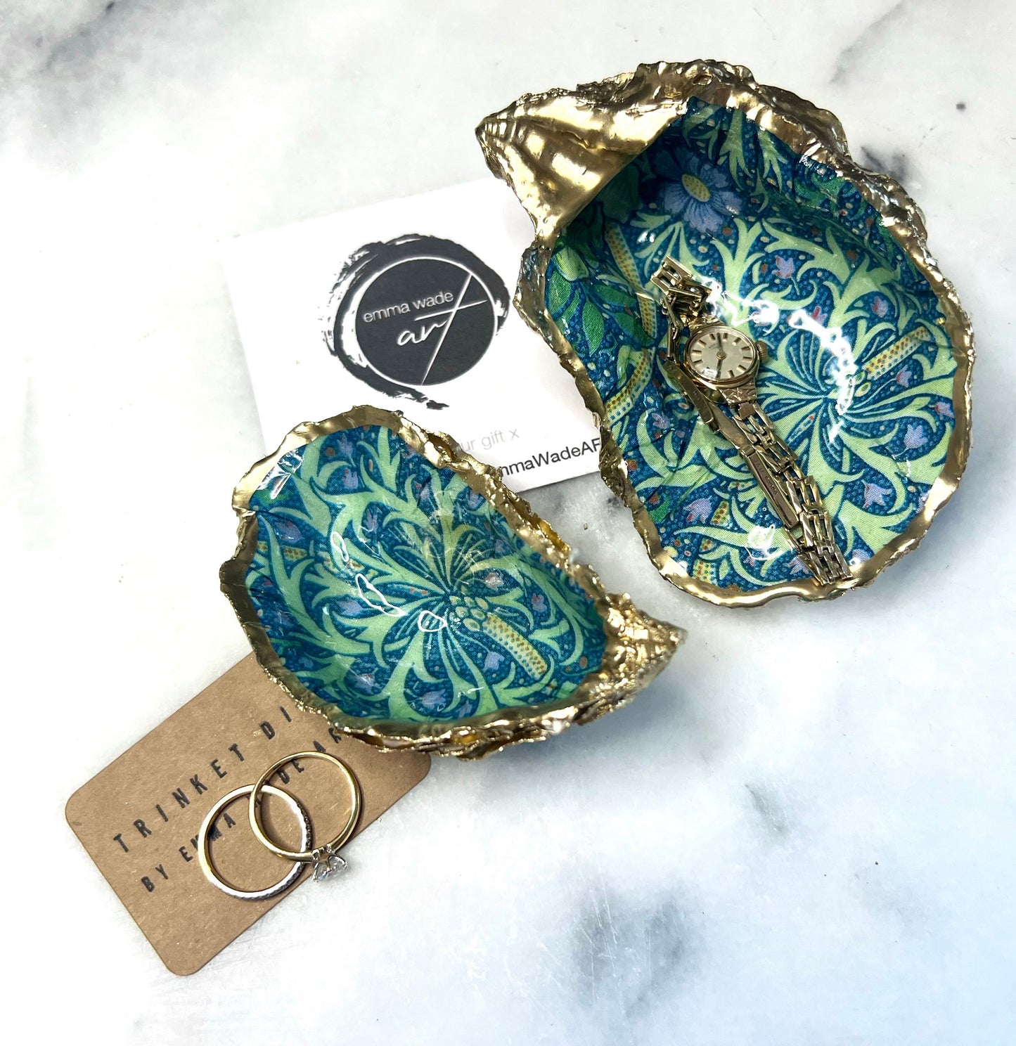 Handmade William Morris inspired oyster shell trinket dish in green and blue tones, finished with gold leaf and sealed with glossy resin. Coastal jewellery dish made from a Dorset oyster shell, featuring a seaweed decoupage design. Perfect for holding rings, earrings and small treasures. Decorative shell bowl photographed on a light background, showing the natural shell shape, detailed pattern and gilded edges.