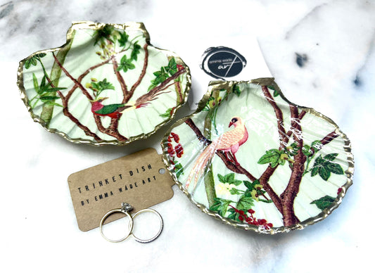 Handmade Dorset scallop shell trinket dish featuring delicate pink bird and botanical branch design with hand gilded gold leaf edging and glossy resin finish, elegant coastal jewellery holder inspired by birds of paradise and nature