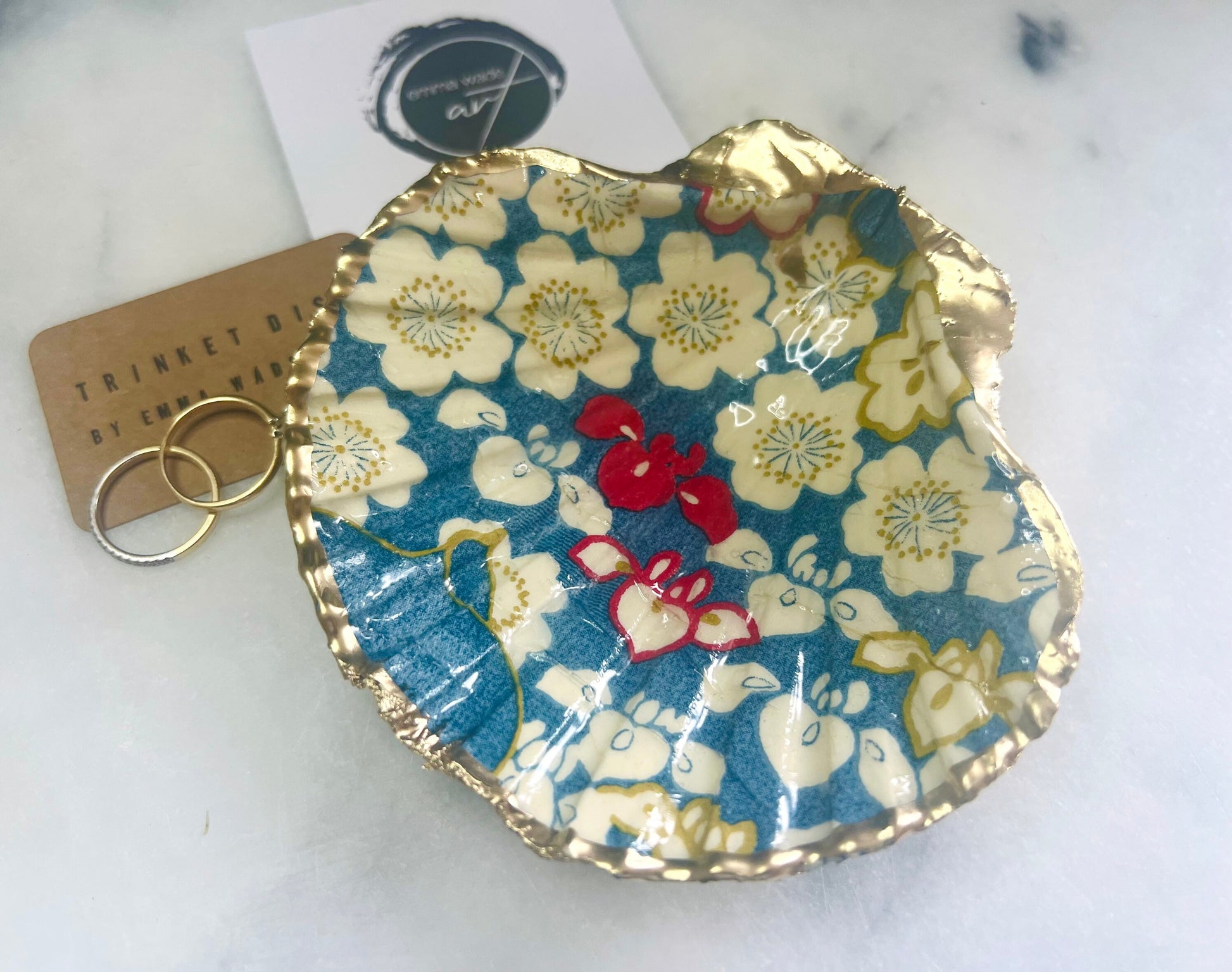 Japanese Sakura cherry blossom floral scallop shell trinket dish with blue, cream and red botanical flower design, hand finished with liquid gold leaf edging and glossy resin. Handmade coastal jewellery tray and ring dish inspired by Japanese floral art and Dorset coastal décor.