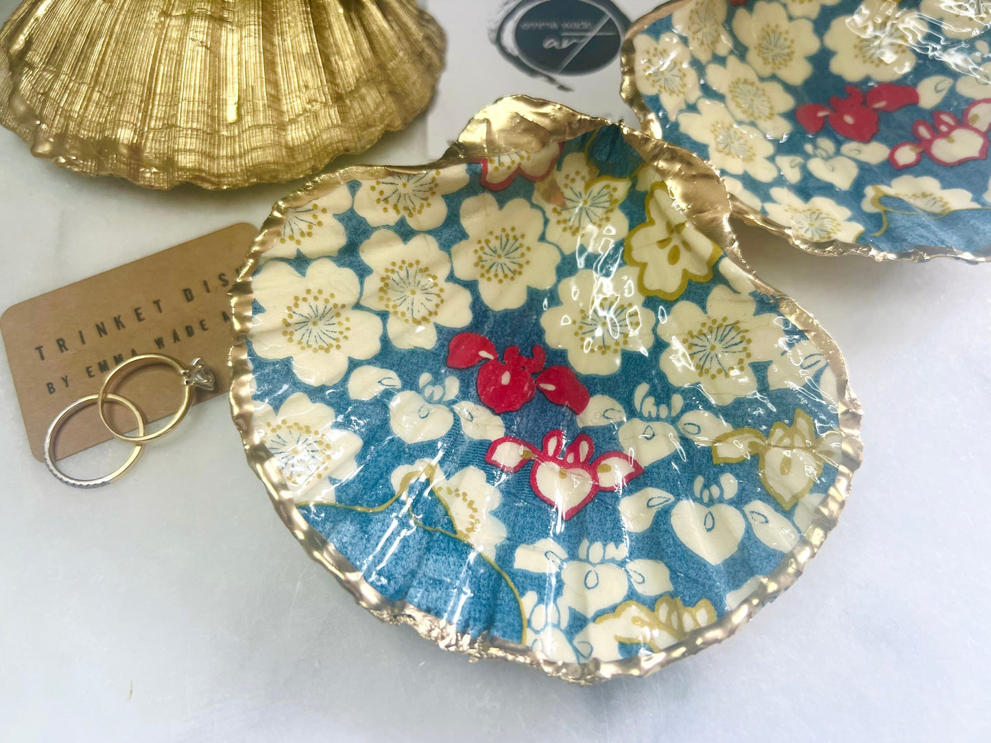 Japanese Sakura cherry blossom floral scallop shell trinket dish with blue, cream and red botanical flower design, hand finished with liquid gold leaf edging and glossy resin. Handmade coastal jewellery tray and ring dish inspired by Japanese floral art and Dorset coastal décor.