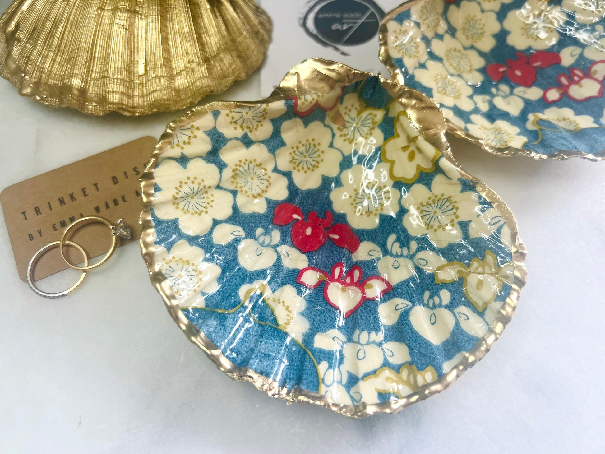 Japanese Sakura cherry blossom floral scallop shell trinket dish with blue, cream and red botanical flower design, hand finished with liquid gold leaf edging and glossy resin. Handmade coastal jewellery tray and ring dish inspired by Japanese floral art and Dorset coastal décor.