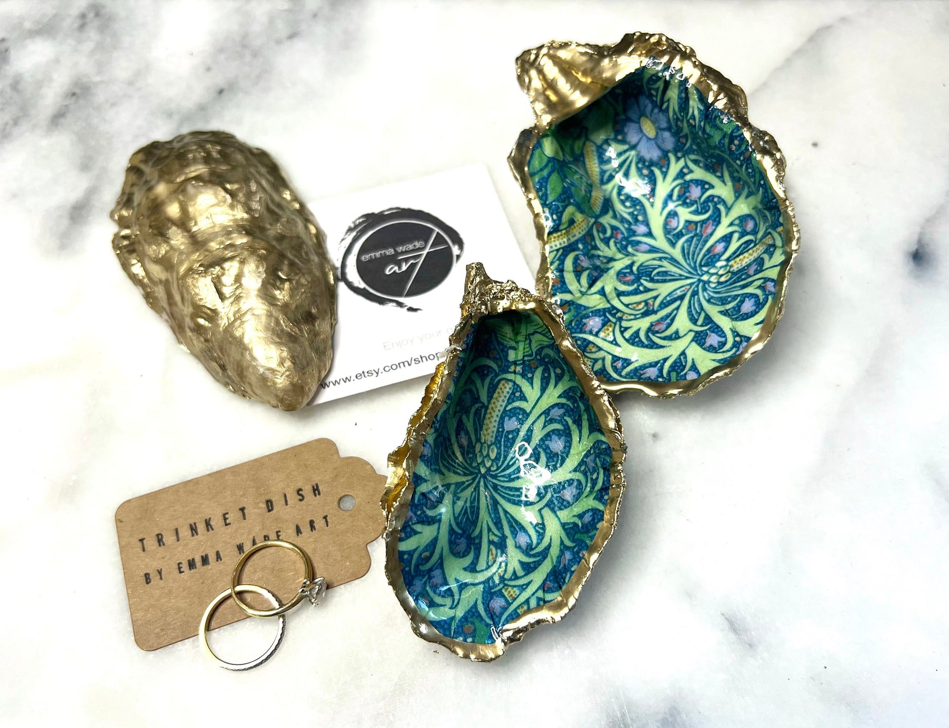 Handmade William Morris inspired oyster shell trinket dish in green and blue tones, finished with gold leaf and sealed with glossy resin. Coastal jewellery dish made from a Dorset oyster shell, featuring a seaweed decoupage design. Perfect for holding rings, earrings and small treasures. Decorative shell bowl photographed on a light background, showing the natural shell shape, detailed pattern and gilded edges.
